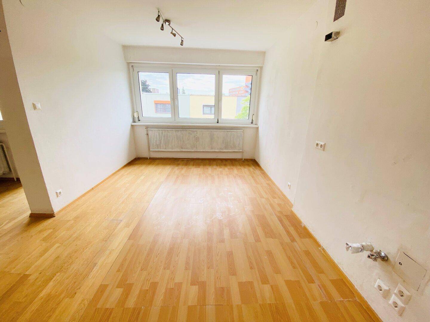 Geräumiges Zimmer mit Parkettboden und großen Fenstern, die für viel Tageslicht sorgen.
