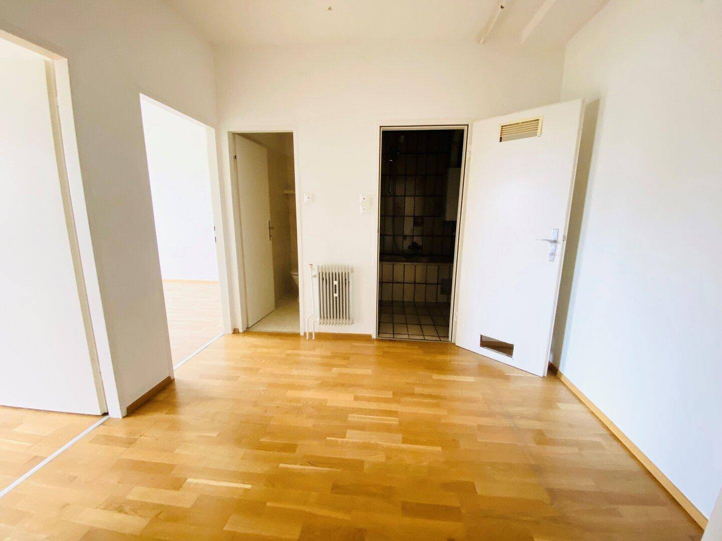 Zentraler Raum mit Parkettboden und mehreren Türen, die zu anderen Zimmern führen.