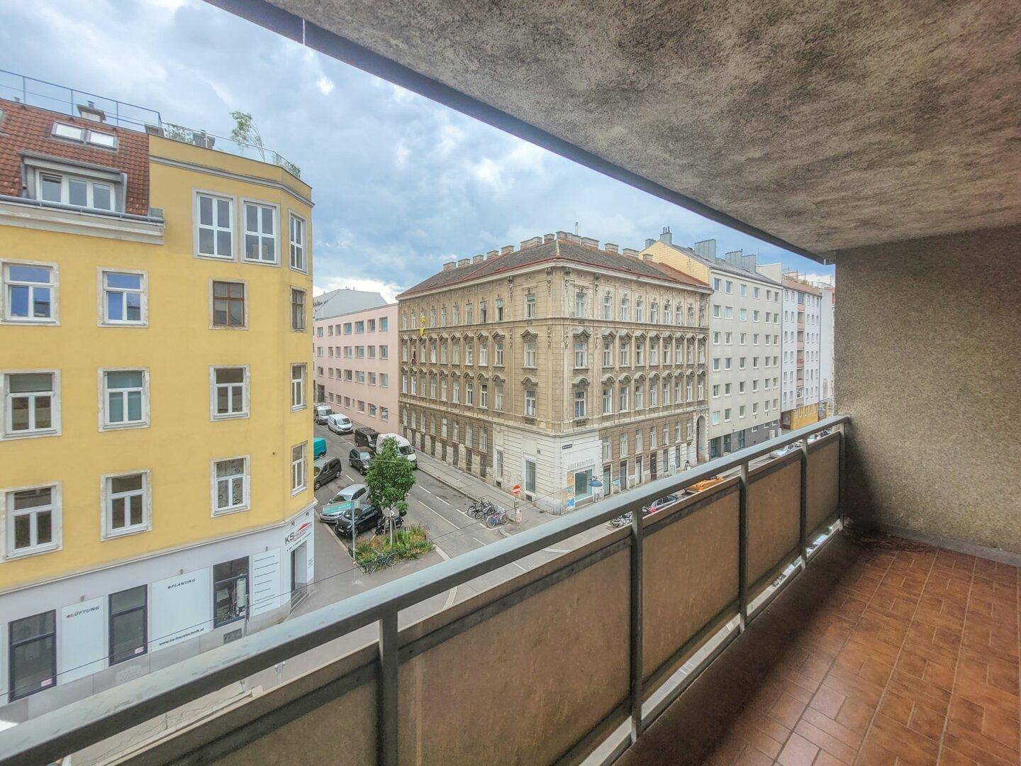 Blick vom Balkon auf die belebte Straße und die umliegenden Stadtgebäude.