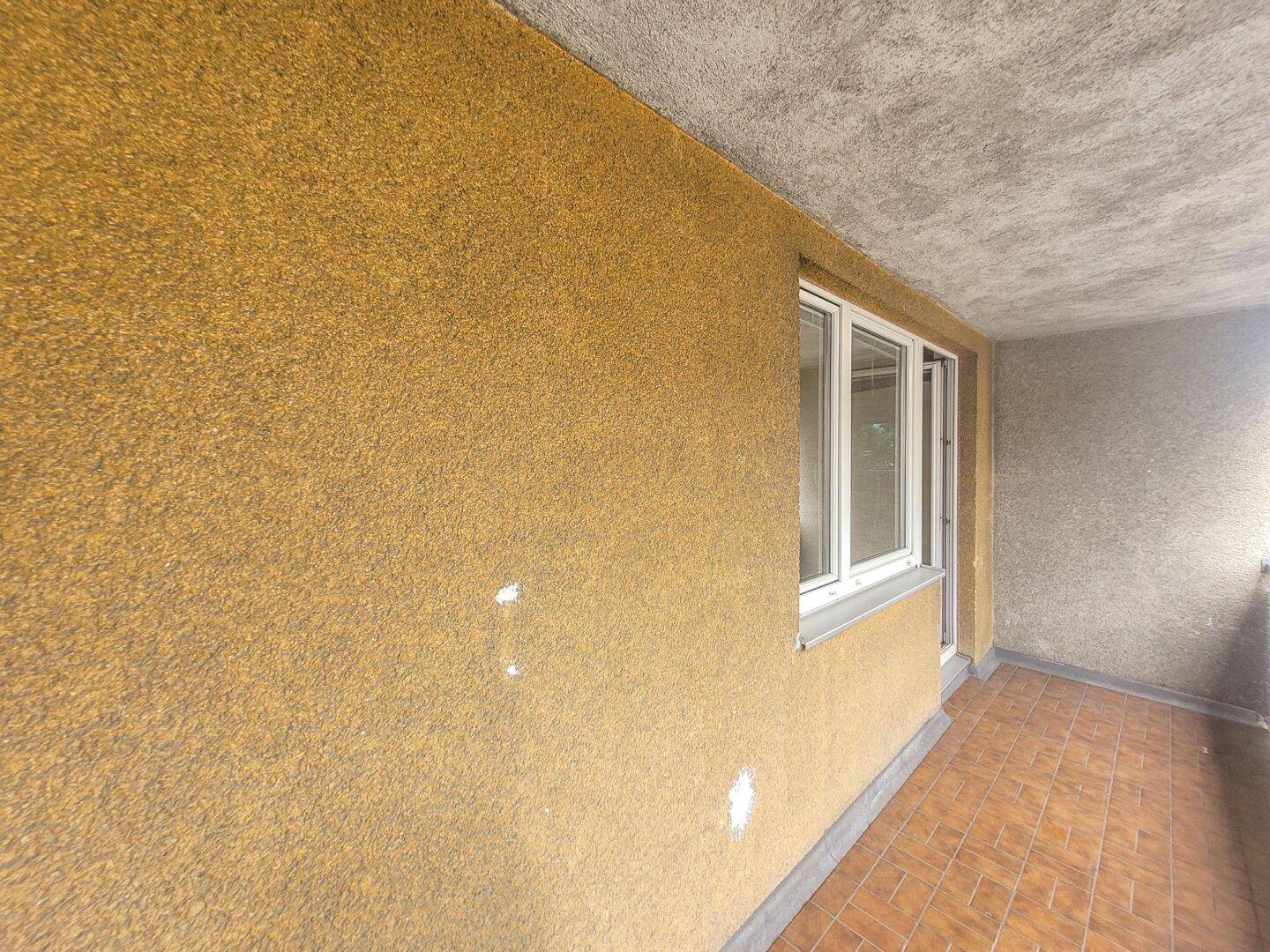 Detailansicht der strukturierten Balkonwand und des gefliesten Bodens.
