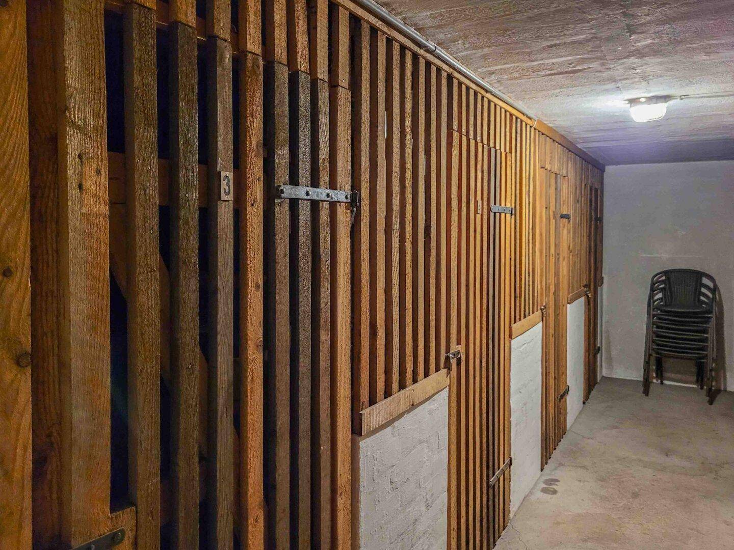 Kellerabteil mit mehreren Lagerfächern aus Holzlatten für zusätzlichen Stauraum.
