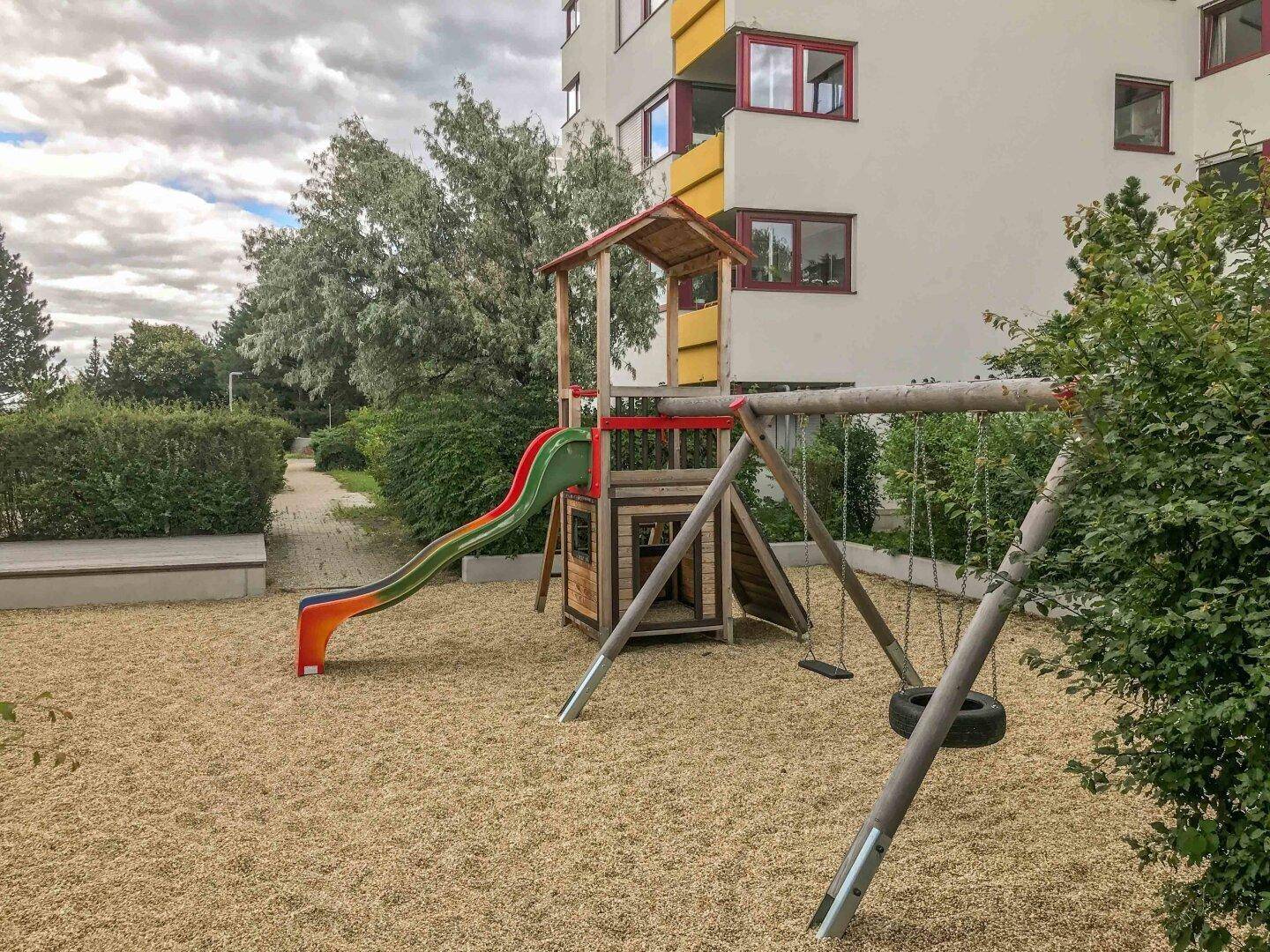 Kinderspielplatz mit Rutsche und Schaukeln im Außenbereich der Wohnanlage.