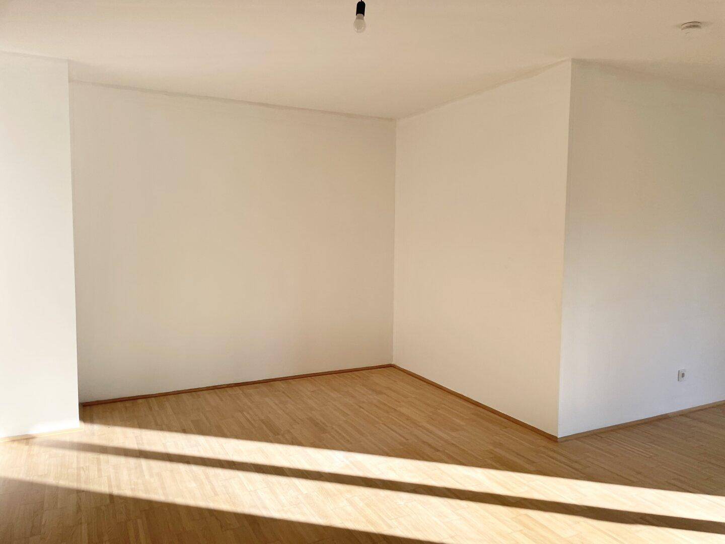 Heller Wohnbereich mit Parkettboden und viel natürlichem Licht, ideal für individuelle Gestaltung.