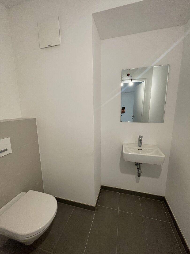 Modernes Gäste-WC mit wandhängender Toilette und kleinem Waschbecken.