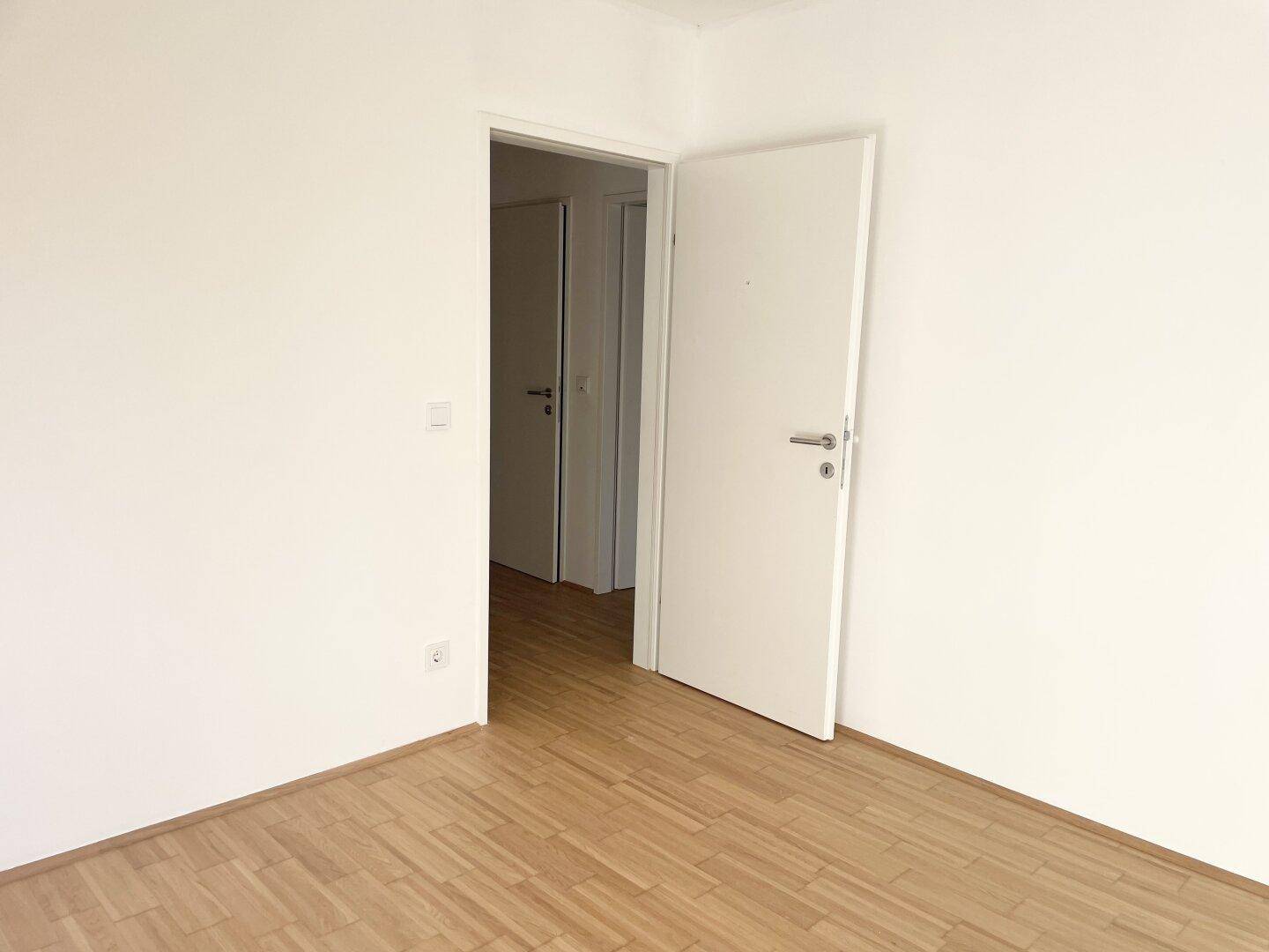 Geräumiges Zimmer mit Parkettboden und weiß gestrichenen Wänden, bereit zur Einrichtung.