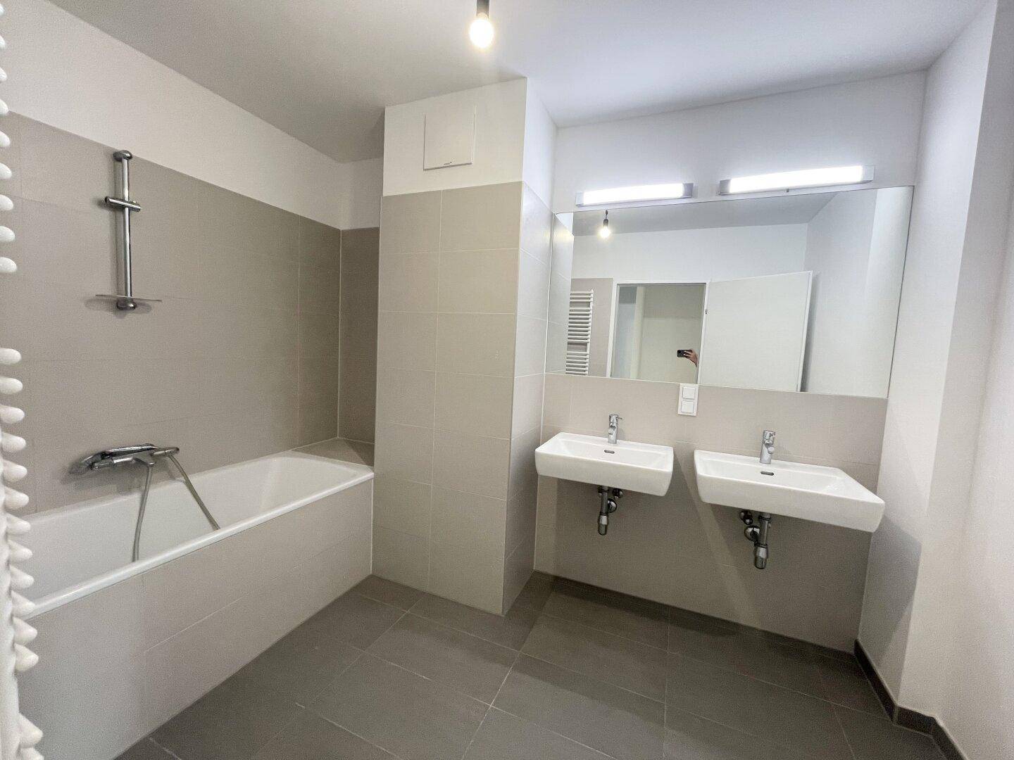 Modernes Badezimmer mit Badewanne, Doppelwaschbecken und großem Spiegel.