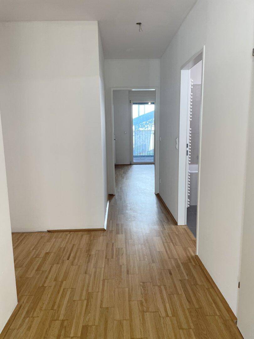Heller Flur mit Parkettboden und Türen zu den angrenzenden Räumen, mit Blick nach draußen.