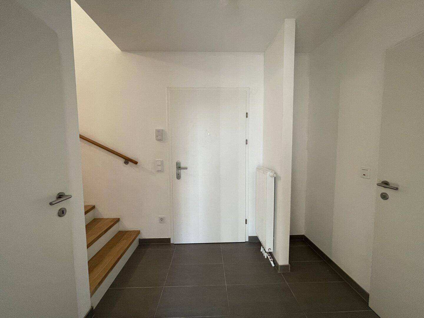 Eingangsbereich mit Haustür, Heizkörper und Treppe zum Obergeschoss.