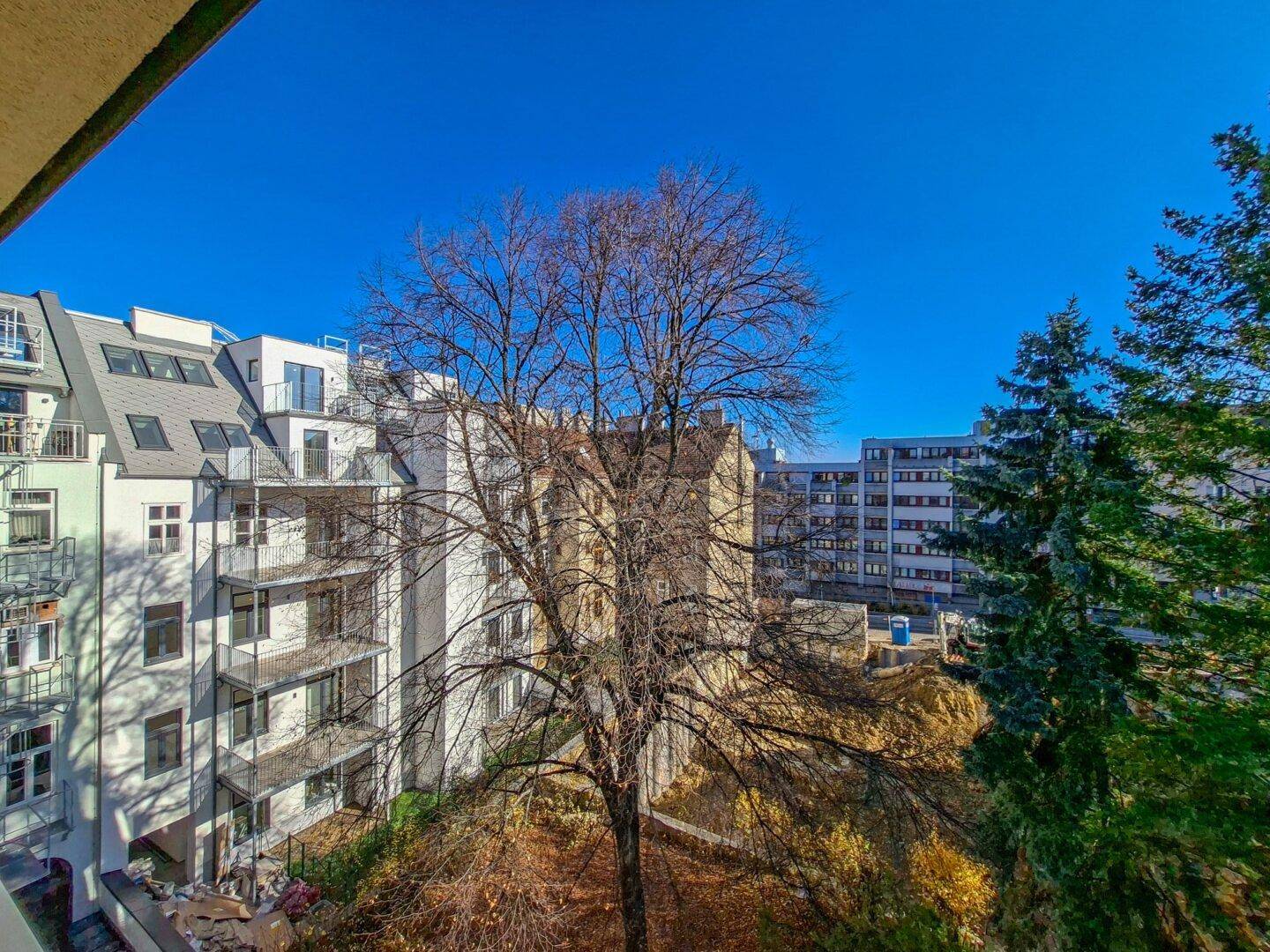 Weitblick vom Balkon auf benachbarte Wohngebäude und herbstliche Bäume.