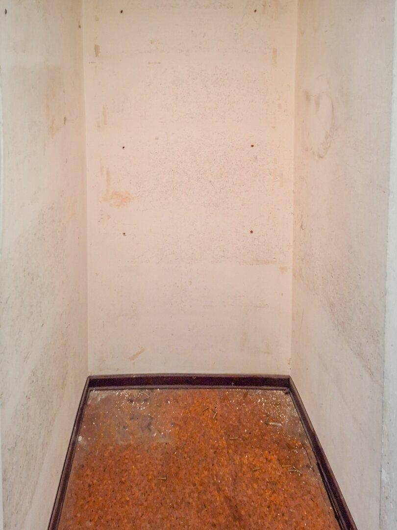 Kleiner Abstellraum mit abgenutztem Boden, ideal für zusätzlichen Stauraum.