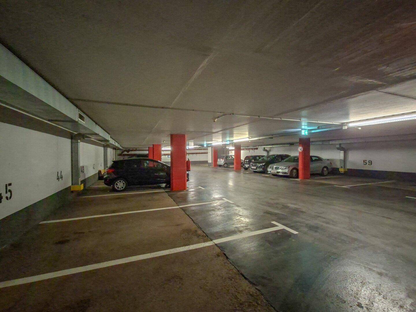 Weitläufige Tiefgarage mit zahlreichen Parkplätzen und geparkten Fahrzeugen.
