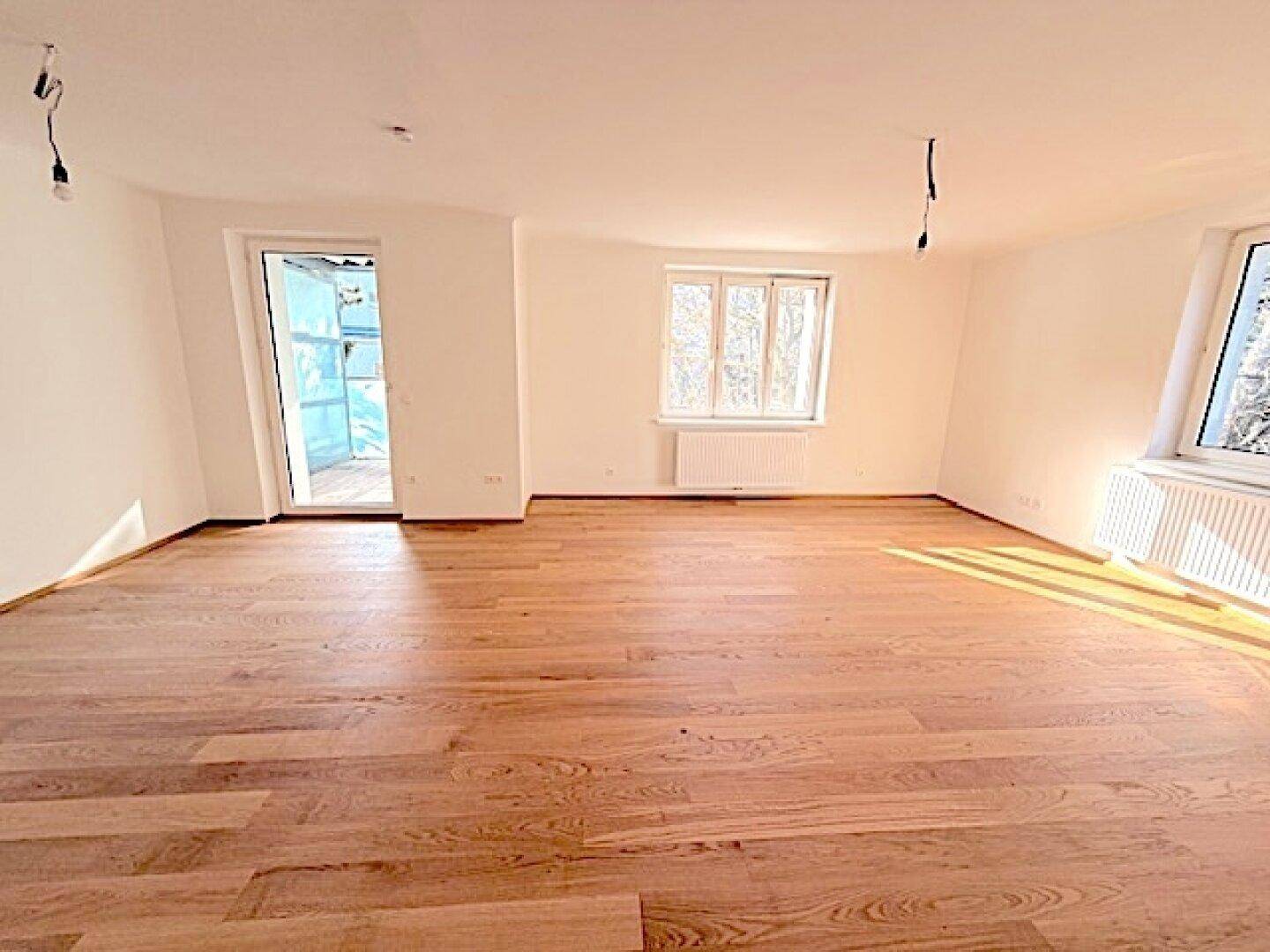 Lichtdurchflutetes Zimmer mit Holzboden und direktem Zugang zu einem Außenbereich.