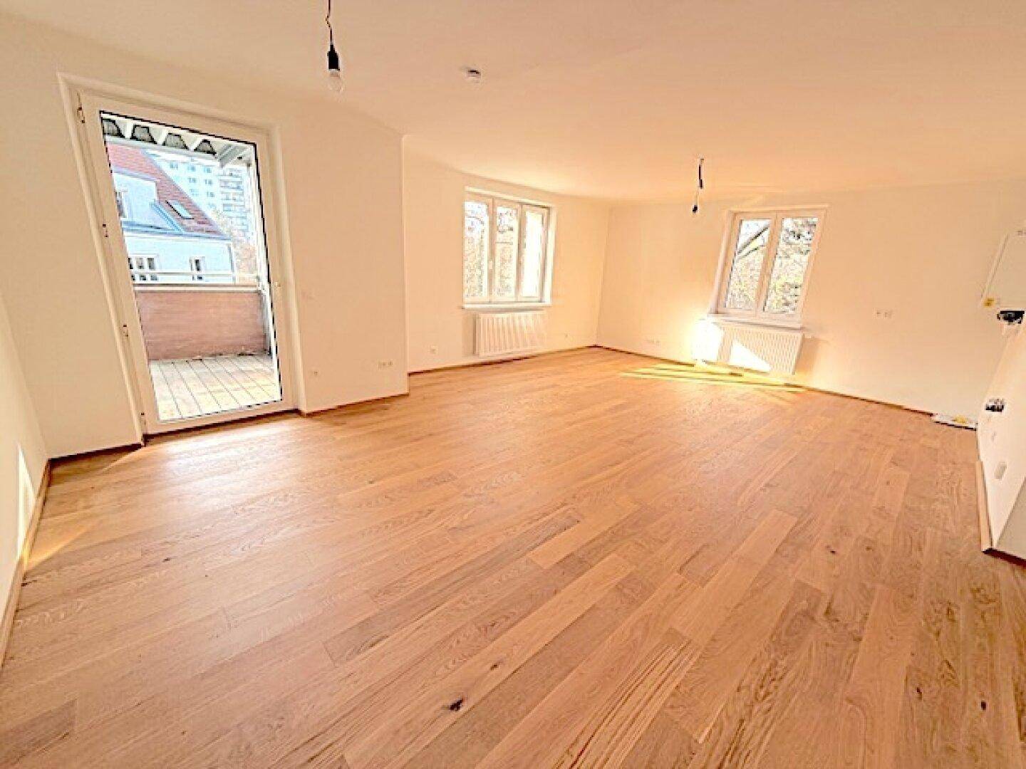 Lichtdurchflutetes Zimmer mit Holzboden und direktem Zugang zu einem Außenbereich.