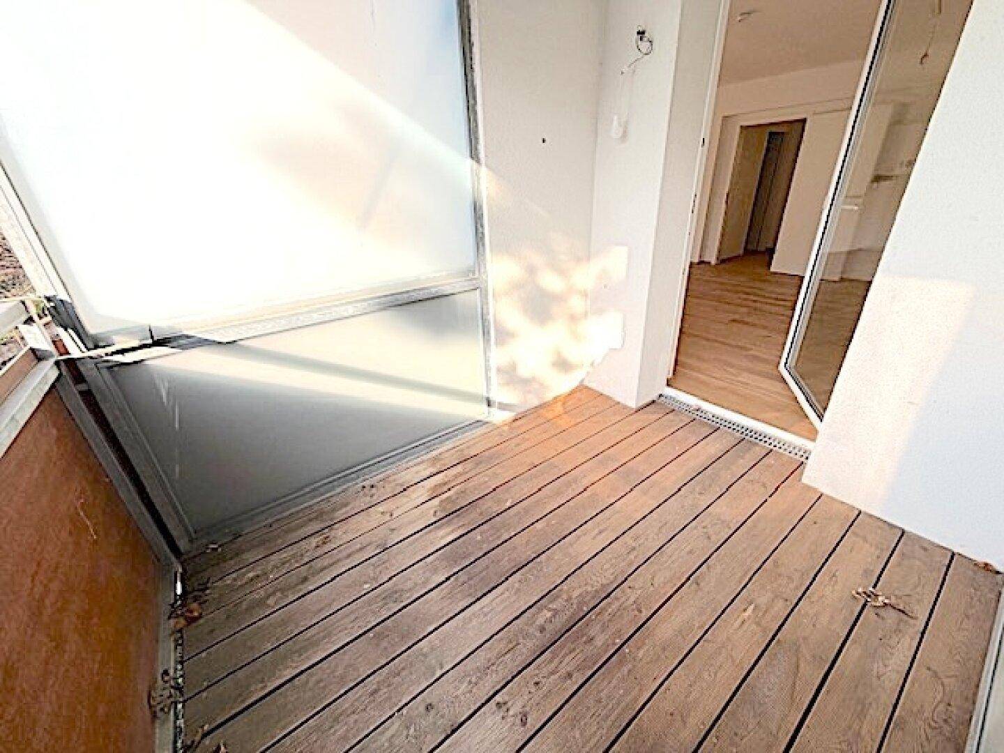 Balkon mit Holzboden und Milchglas-Seitenwänden, bietet direkten Zugang zum Innenbereich.
