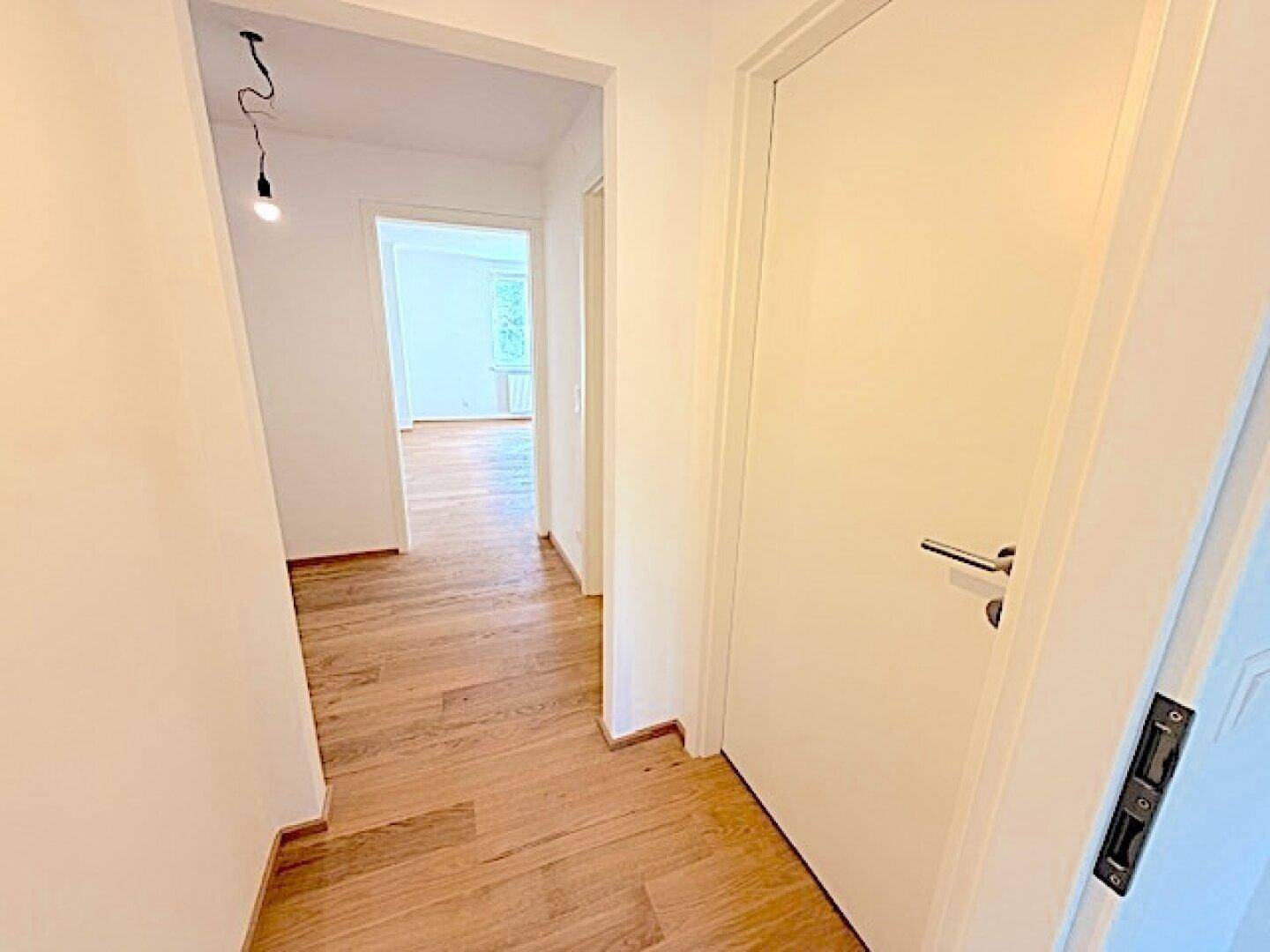 Heller Flur mit Holzparkettboden, der zu weiteren Räumen der Wohnung führt.