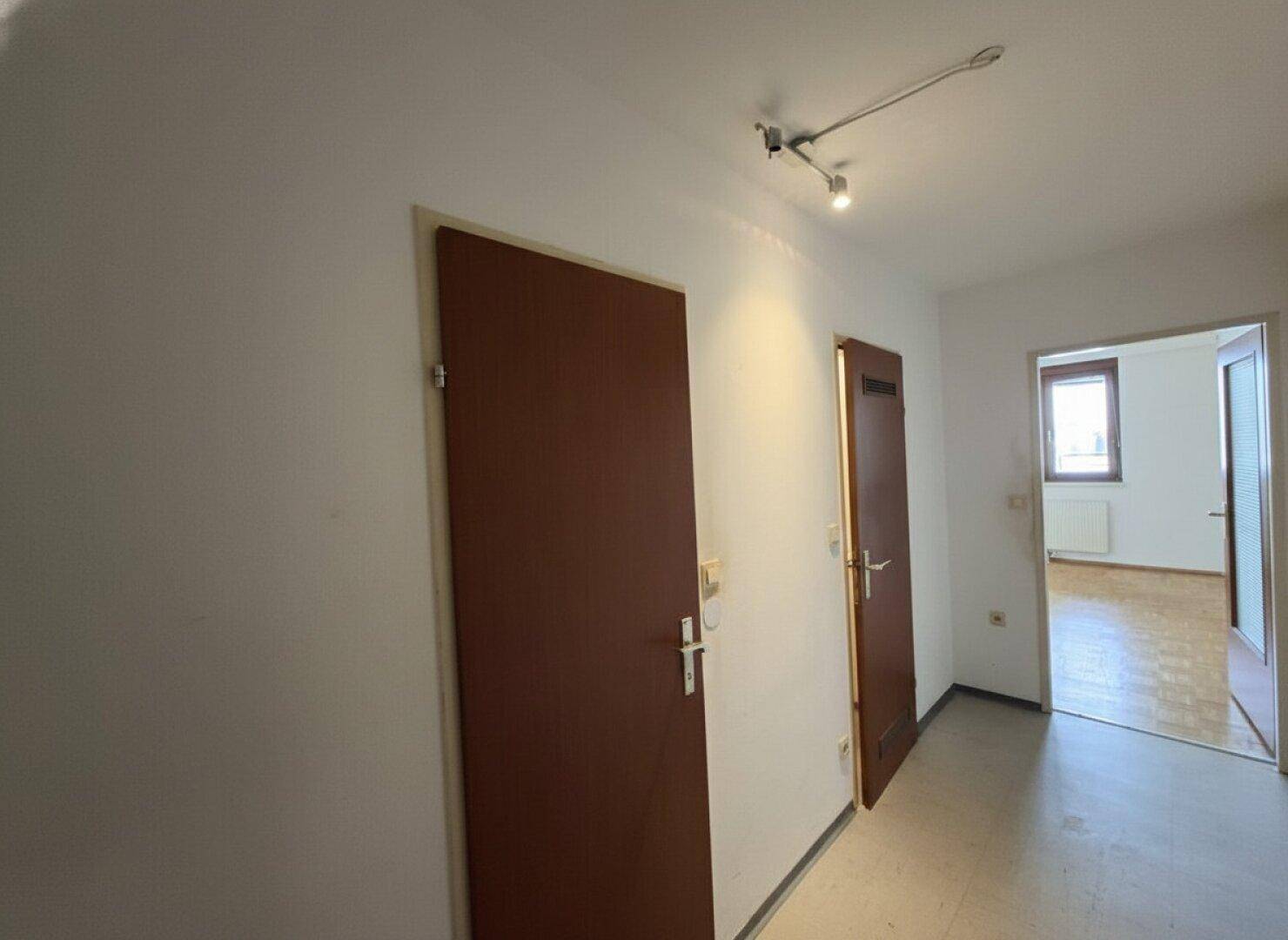 Heller Flur mit mehreren Türen und Blick in angrenzende Räume.