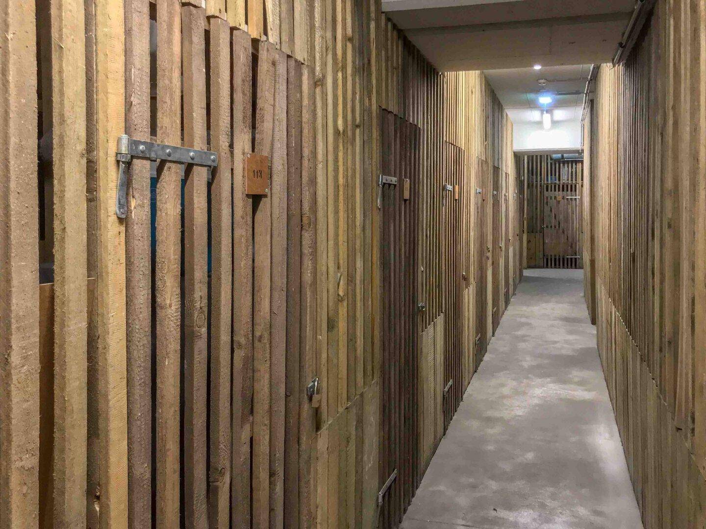 Langer Flur mit vielen individuellen Lagerabteilen aus Holz im Kellerbereich.