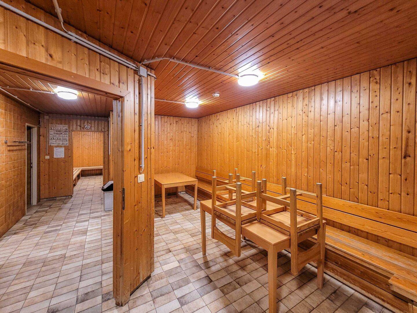 Gemeinschaftlicher Wellnessbereich mit Holzbänken und Tischen, ideal zur Entspannung.