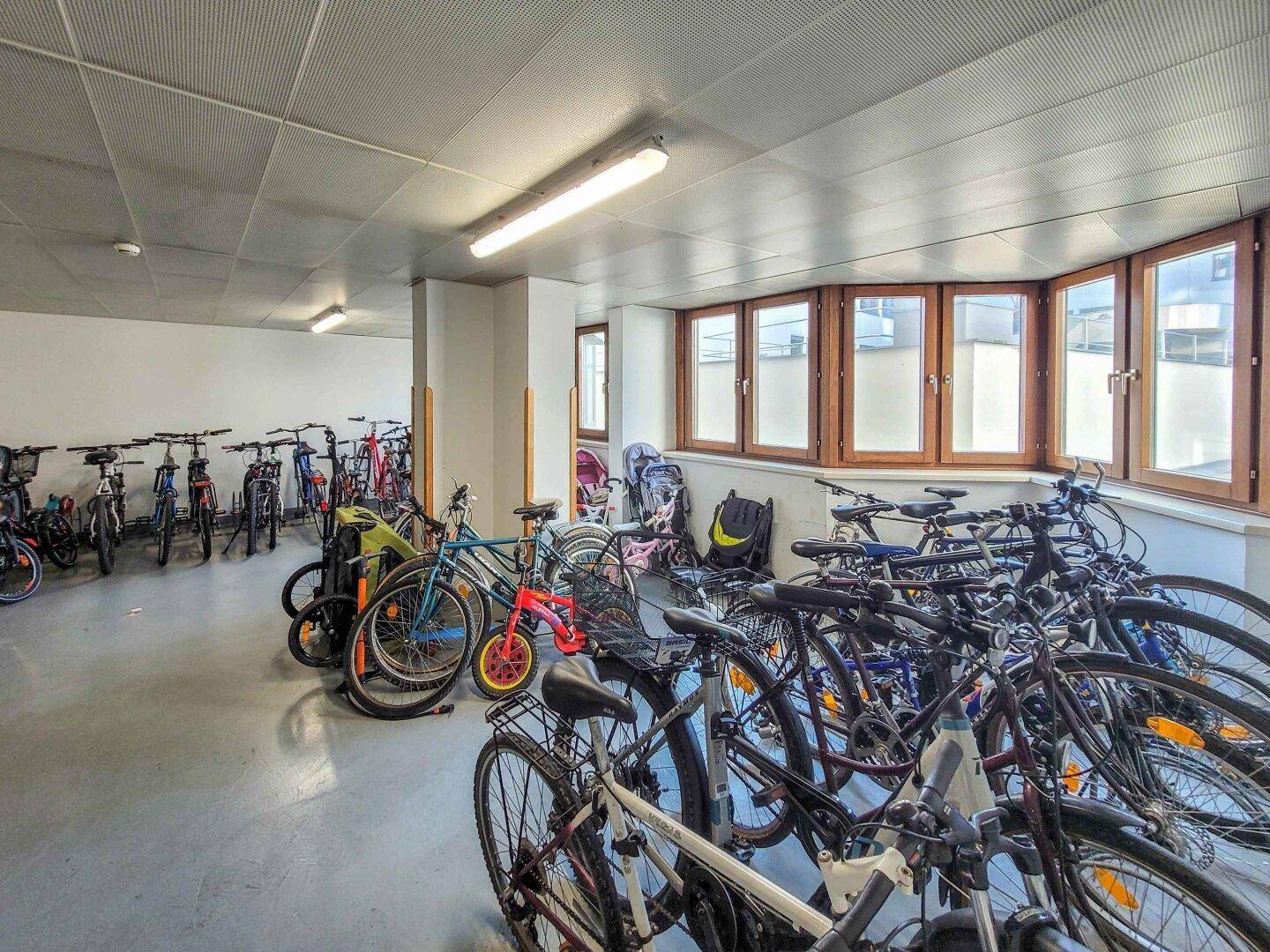Geräumiger Fahrradraum mit vielen Stellplätzen und Fenstern für Tageslicht.