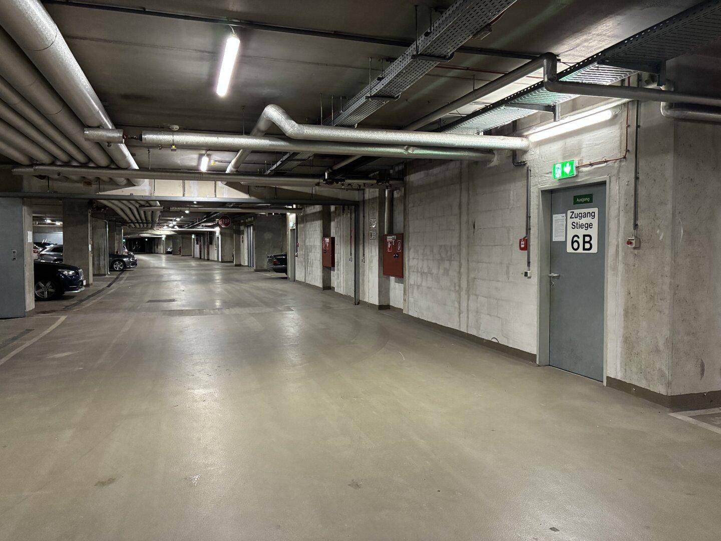 Tiefgarage mit Fluchtwegtür und Brandschutzvorrichtungen entlang der Betonwand.