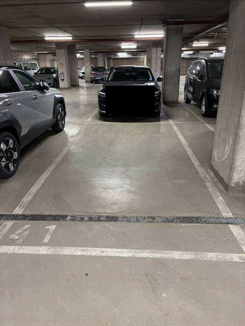 Markierter Stellplatz in der Tiefgarage, umgeben von weiteren geparkten Fahrzeugen.