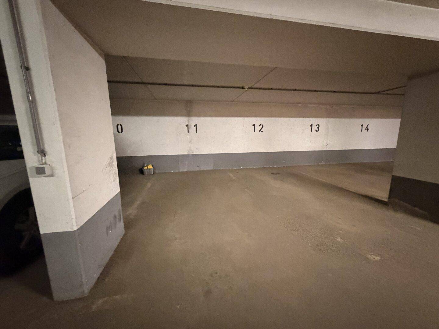 Geräumiger Tiefgaragenstellplatz mit Betonboden und nummerierten Parkplätzen in einem gepflegten Zustand.