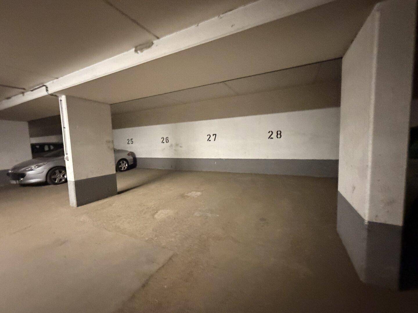 Sauberer Tiefgaragenstellplatz mit Betonboden und klar gekennzeichneten Parknummern in einem funktionalen Zustand.