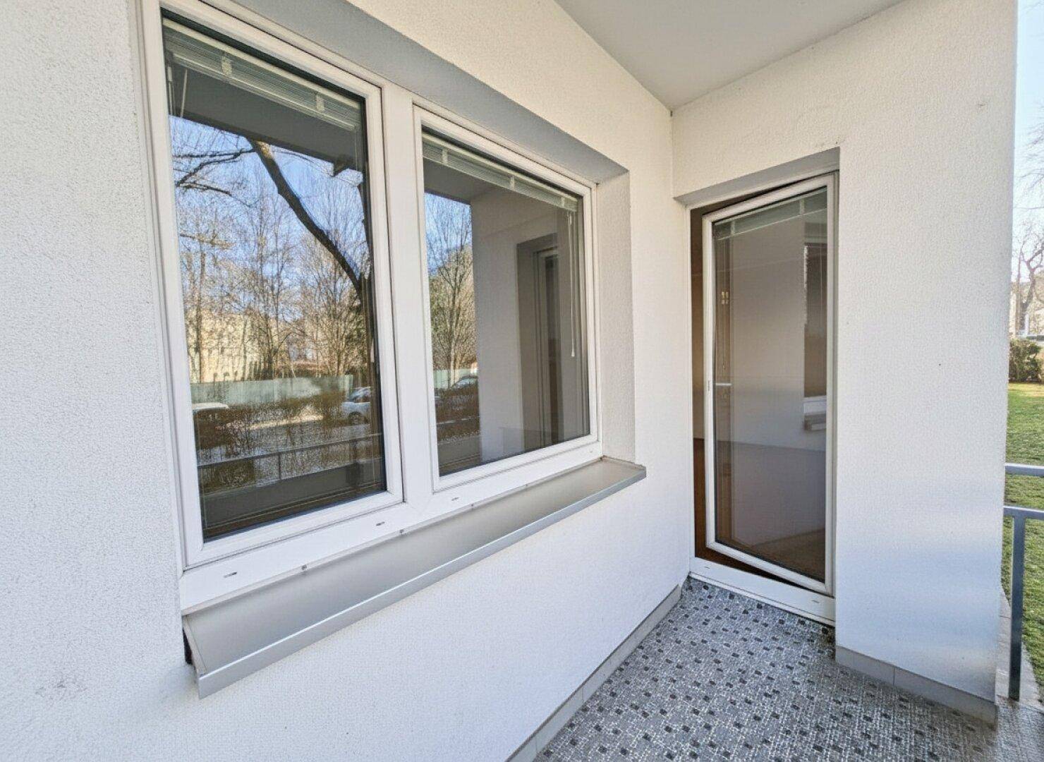 Kleiner Balkonbereich mit Fliesenboden und Zugang zu einem Innenraum durch eine Glastür.