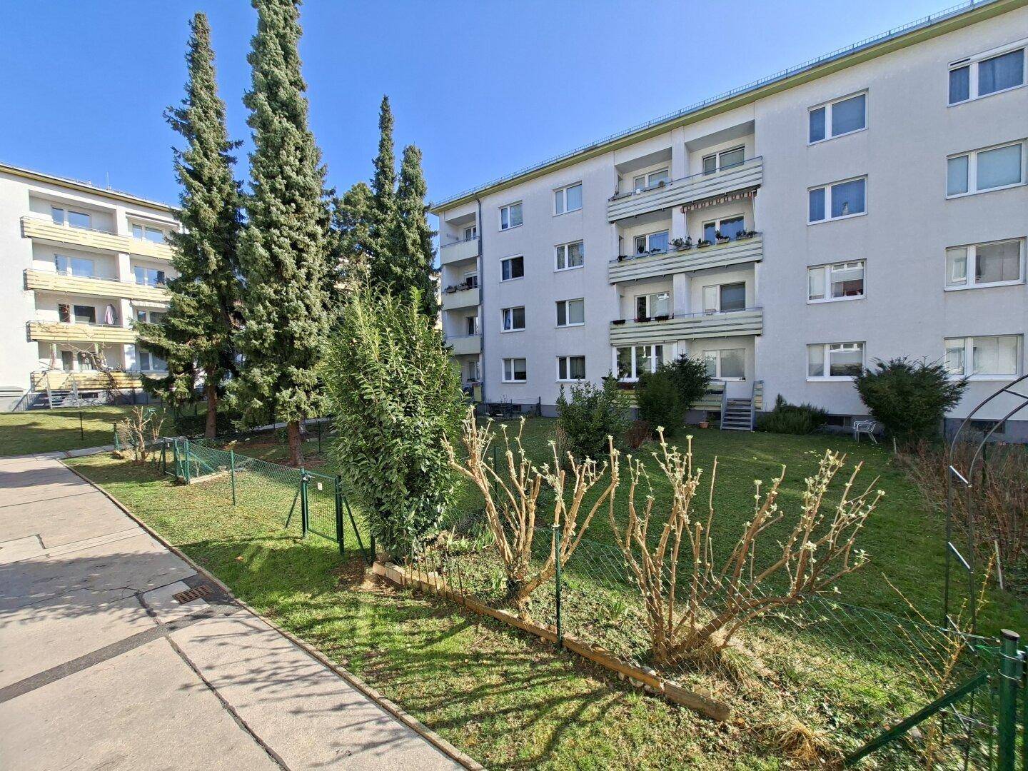 Mehrfamilienhaus mit Balkonen und einer gepflegten Grünfläche im Vordergrund.
