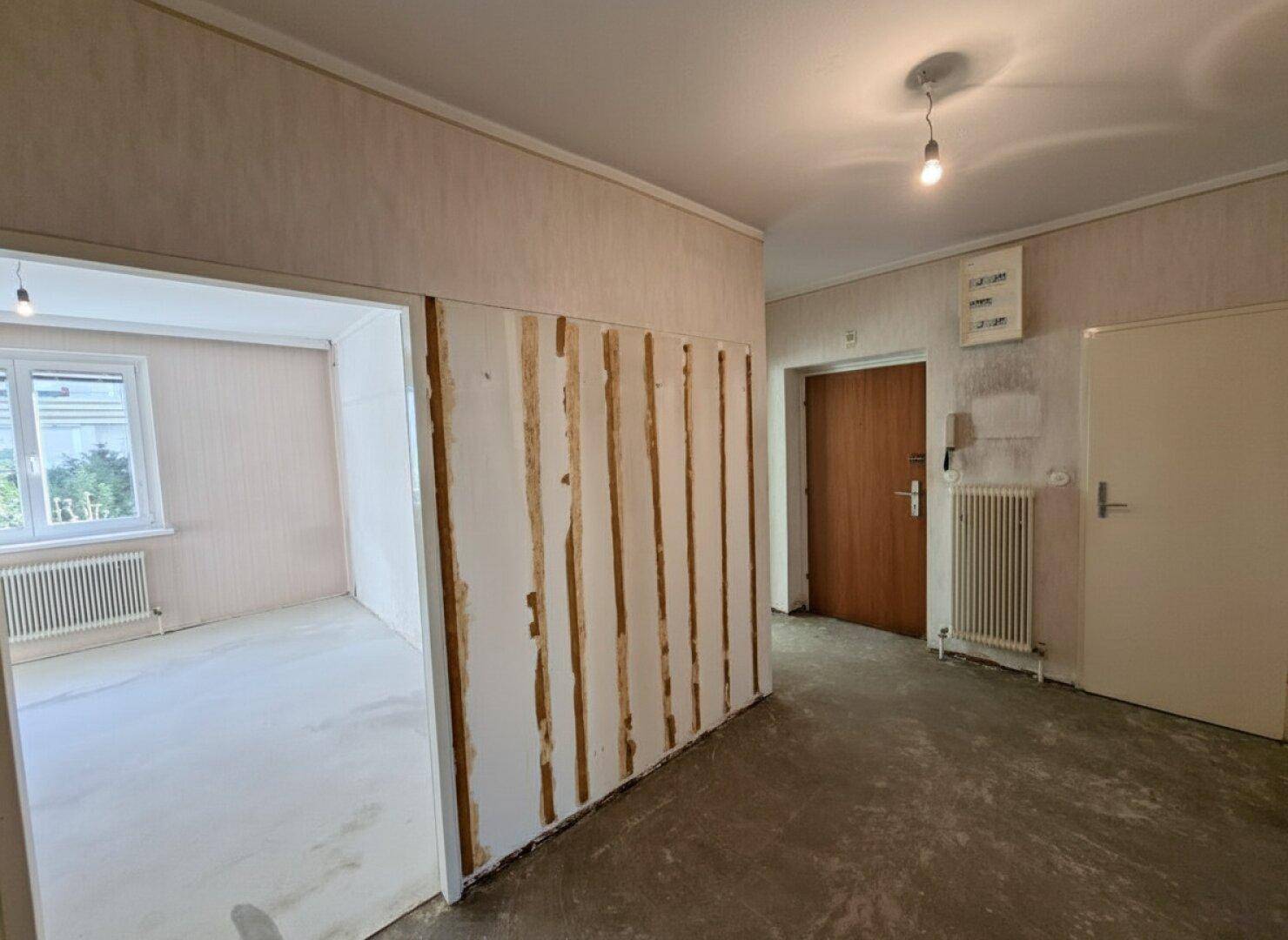 Eingangsbereich mit mehreren Türen und einem Heizkörper, der auf eine Modernisierung wartet.