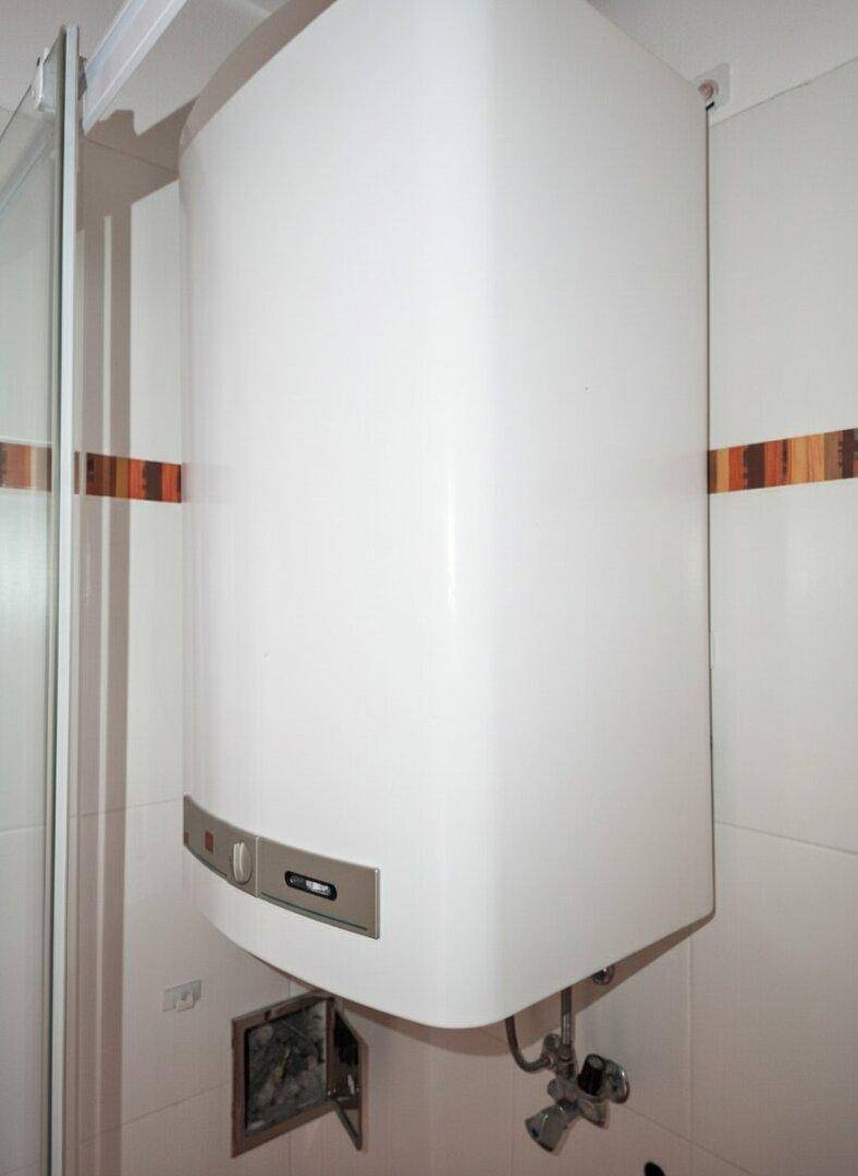Nahaufnahme eines Warmwasserboilers im Badezimmer, montiert über dem Waschbecken.