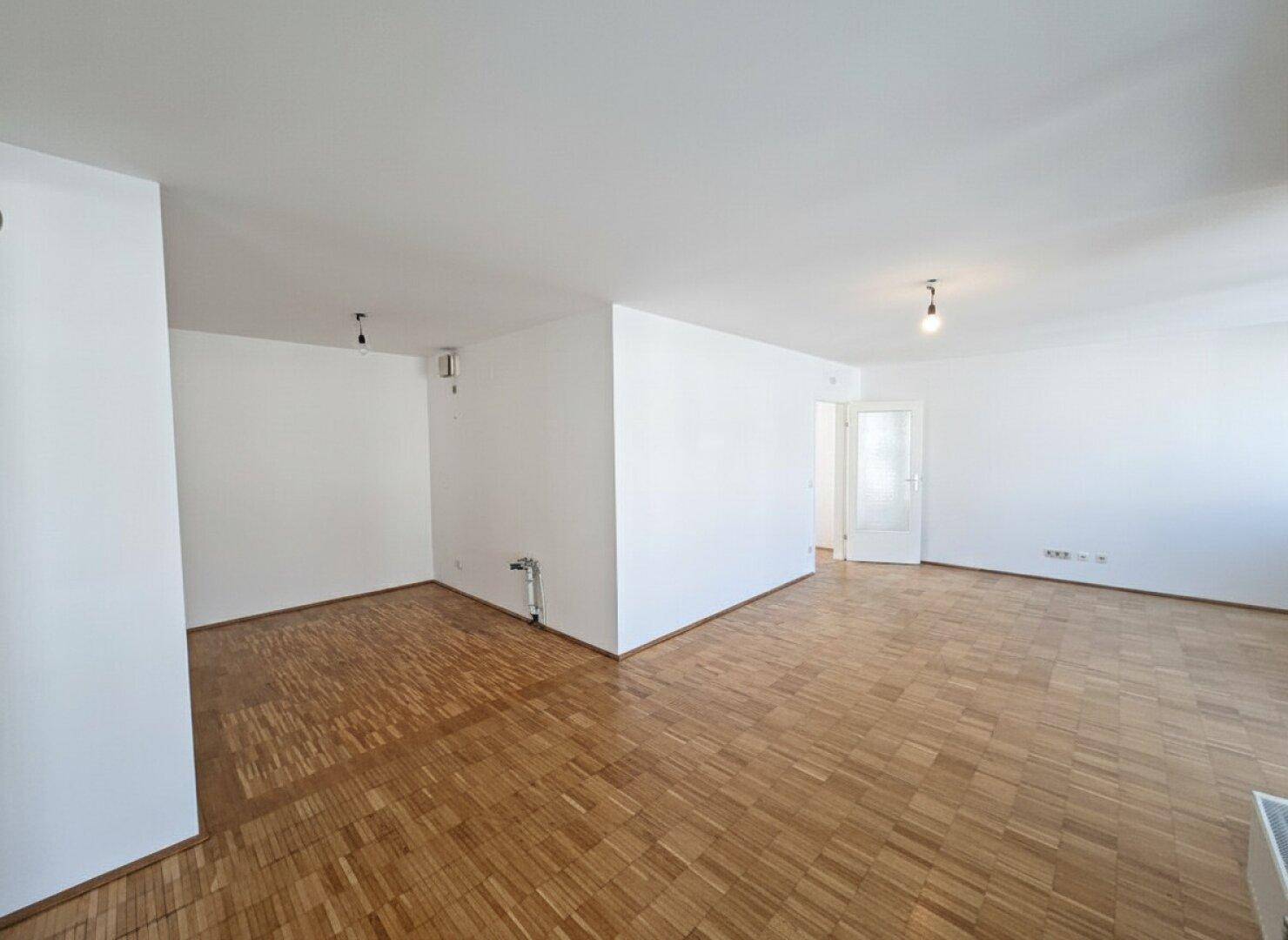 Geräumiger, leerer Raum mit Parkettboden und weiß gestrichenen Wänden, bereit zur individuellen Gestaltung.