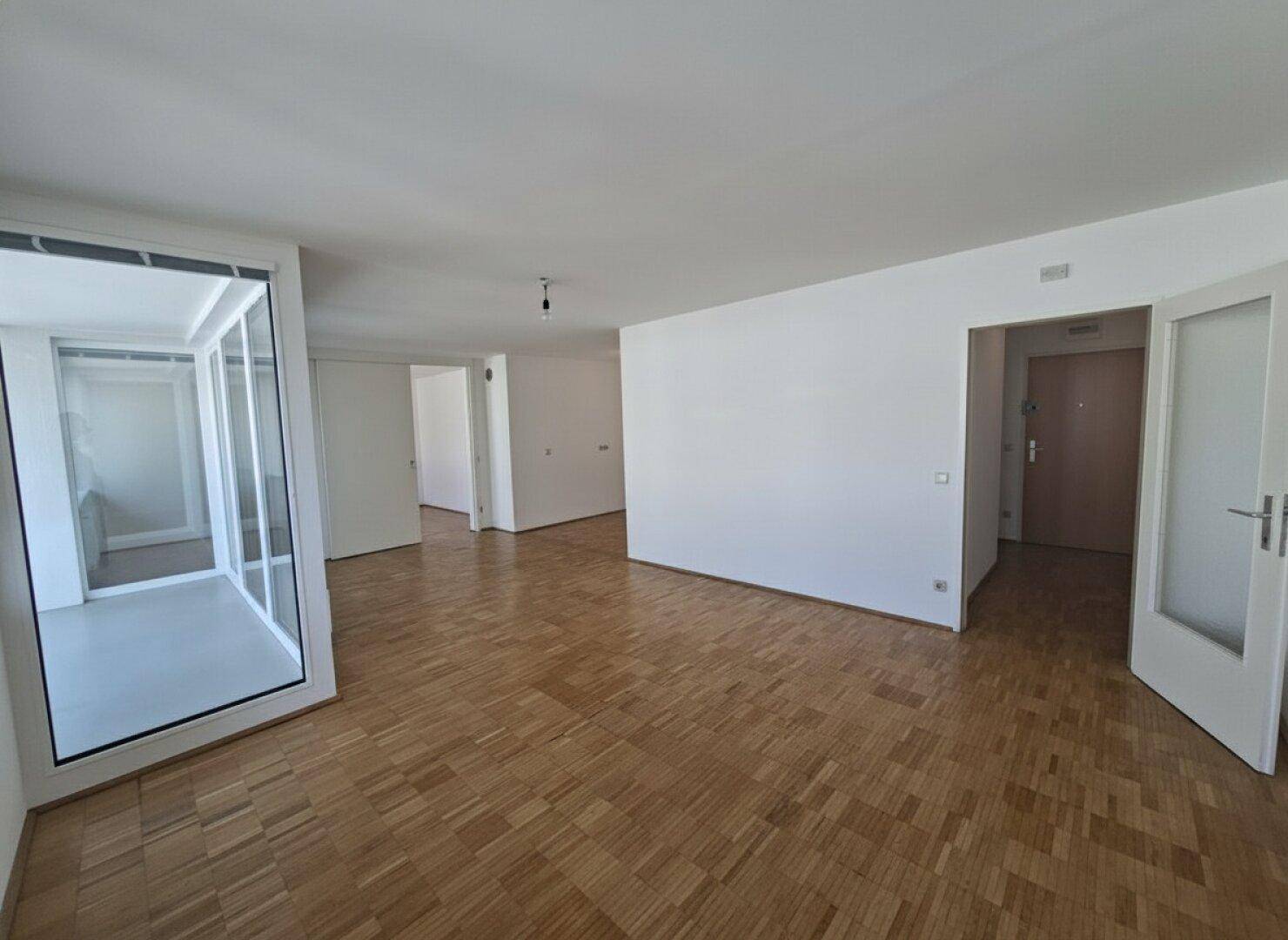 Heller Flur mit Parkettboden und Zugang zu verschiedenen Räumen, inklusive der verglasten Loggia.