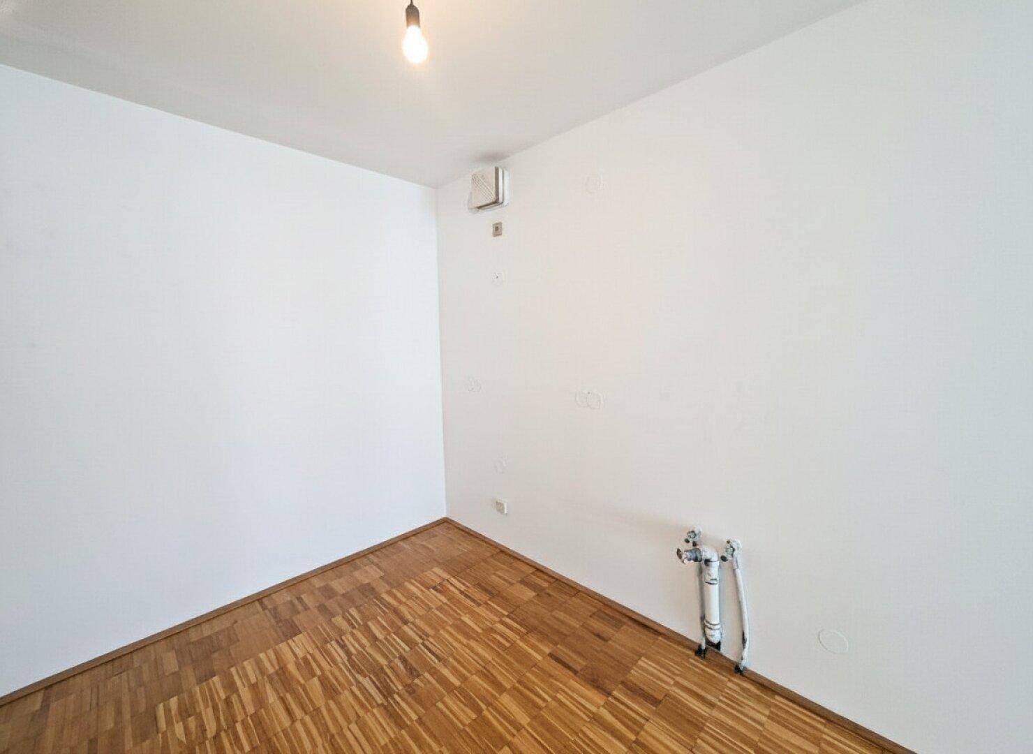 Kleiner Raum mit Parkettboden und Anschlüssen, ideal als Abstellraum oder für Waschmaschine.