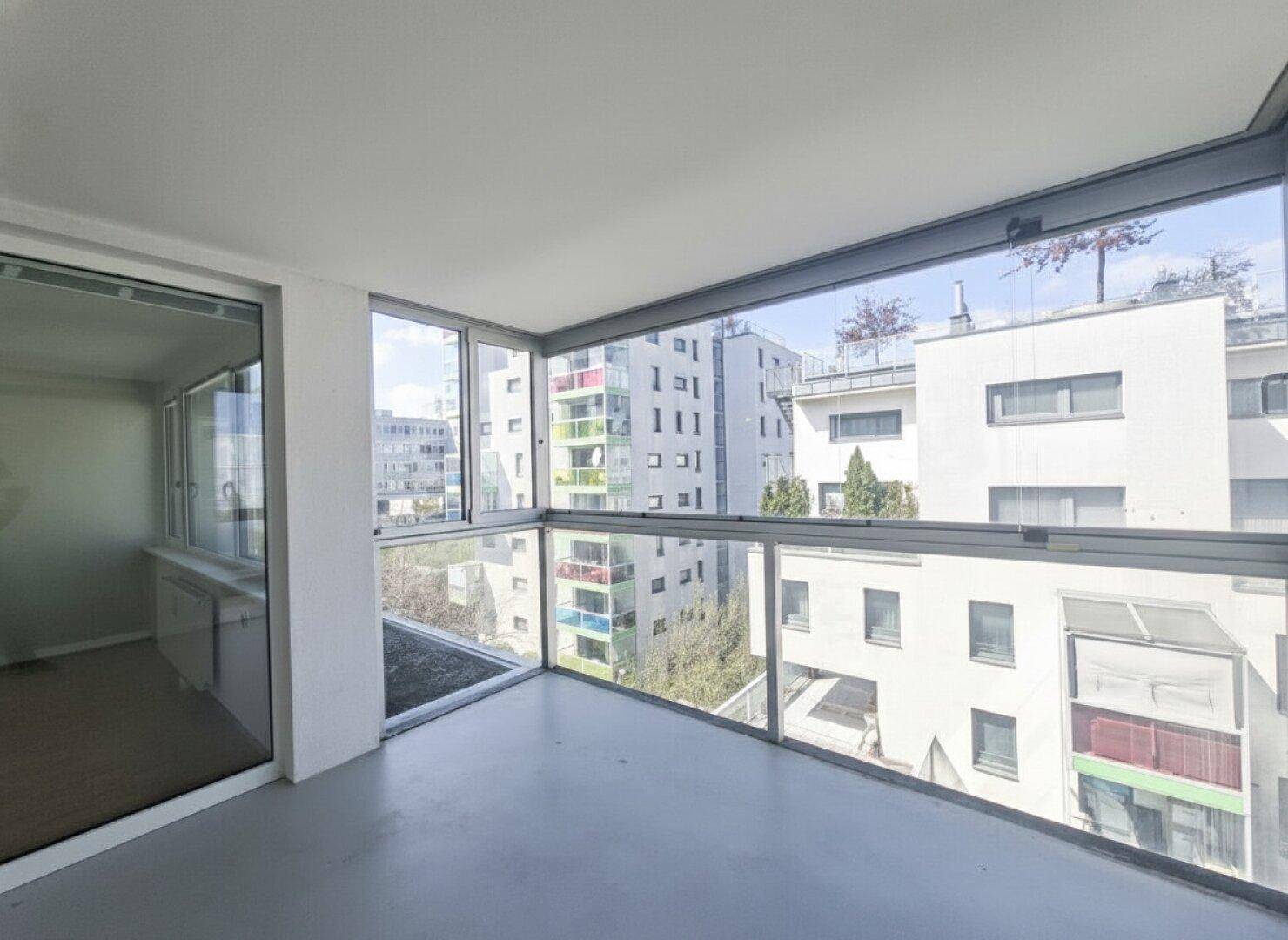 Verglaste Loggia mit weitem Blick auf die umliegenden Gebäude und viel Tageslicht.