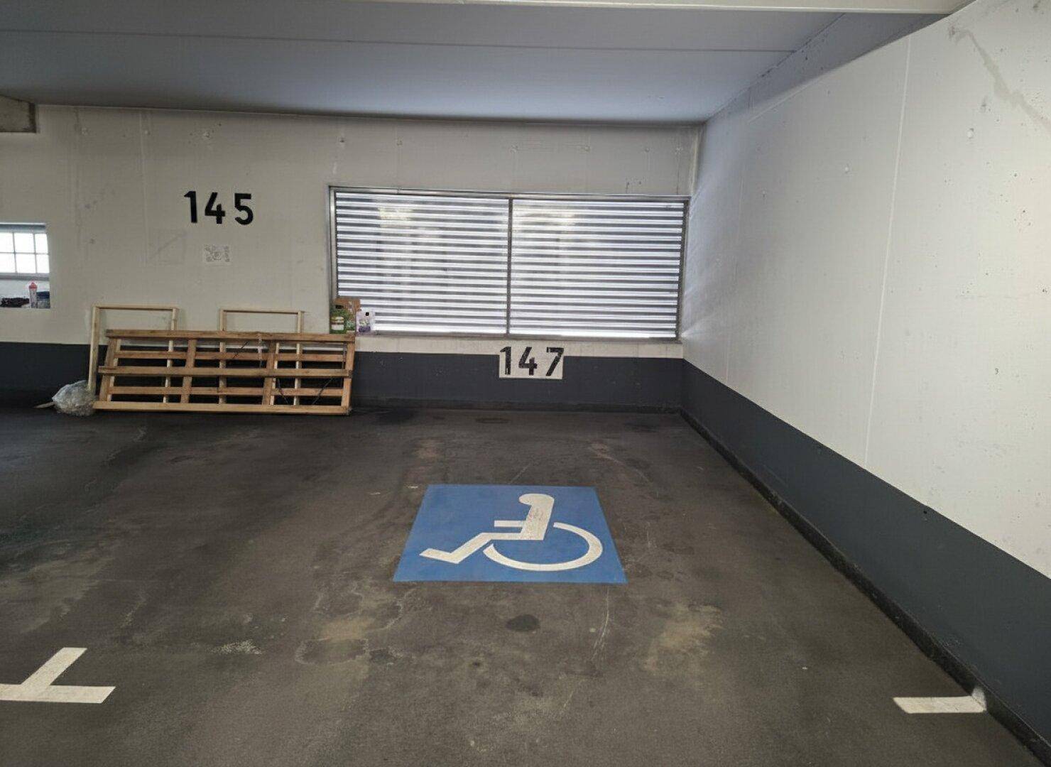 Barrierefreier Parkplatz in der Tiefgarage mit Rollstuhl-Symbol und Nummerierung.