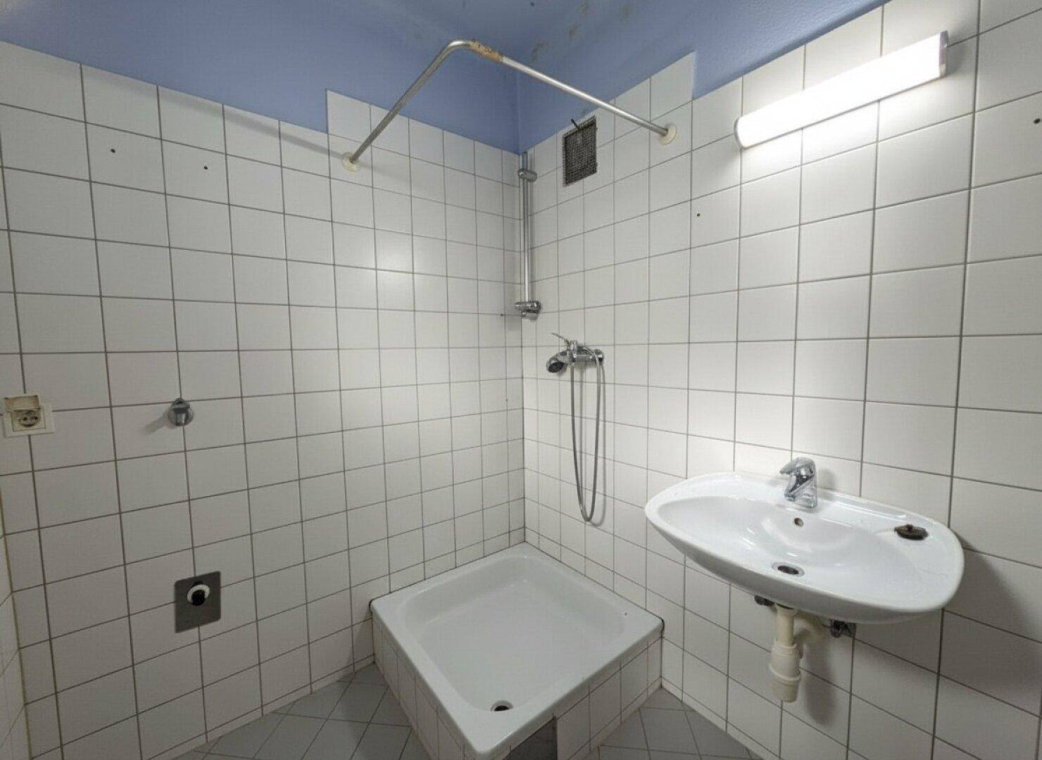 Badezimmer mit Duschwanne, Waschbecken und weißen Fliesen an den Wänden.
