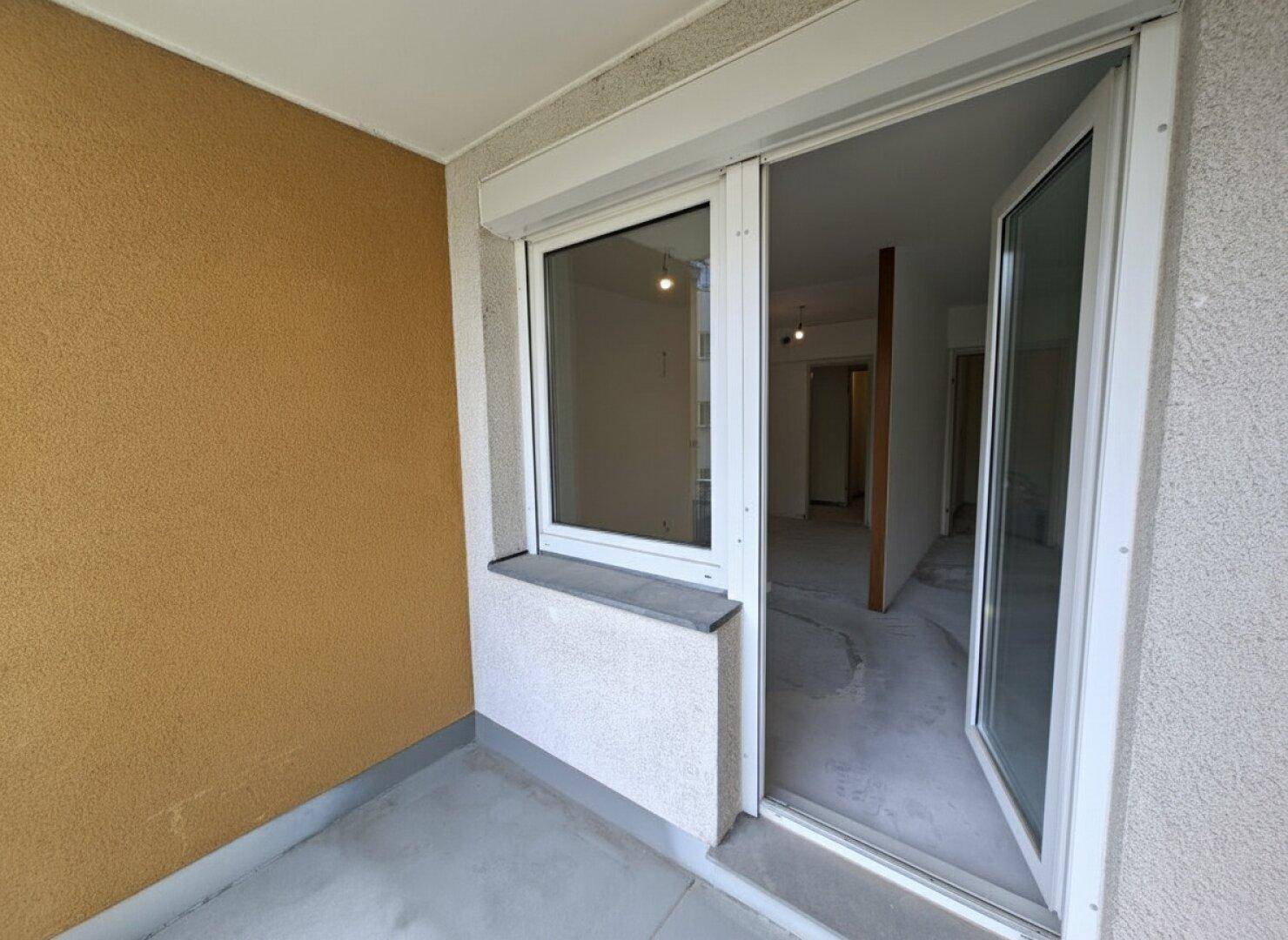 Kleiner Balkon mit Rollladen und Zugang zum unmöblierten Innenraum der Wohnung.