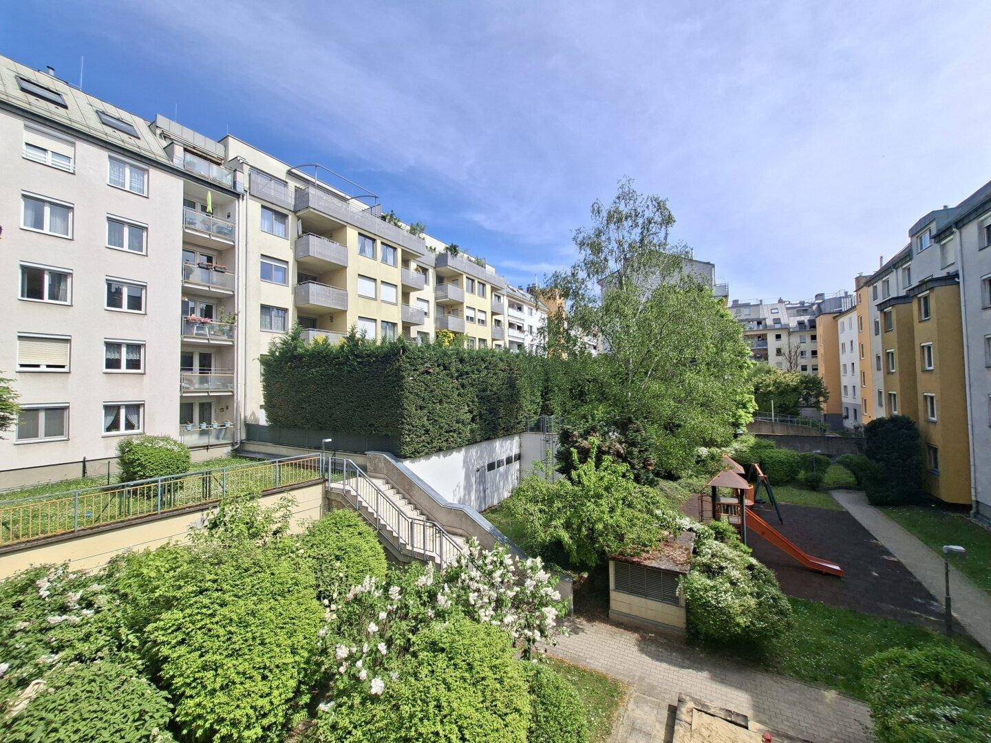 Außenansicht der Wohnanlage mit begrüntem Innenhof und Kinderspielplatz.