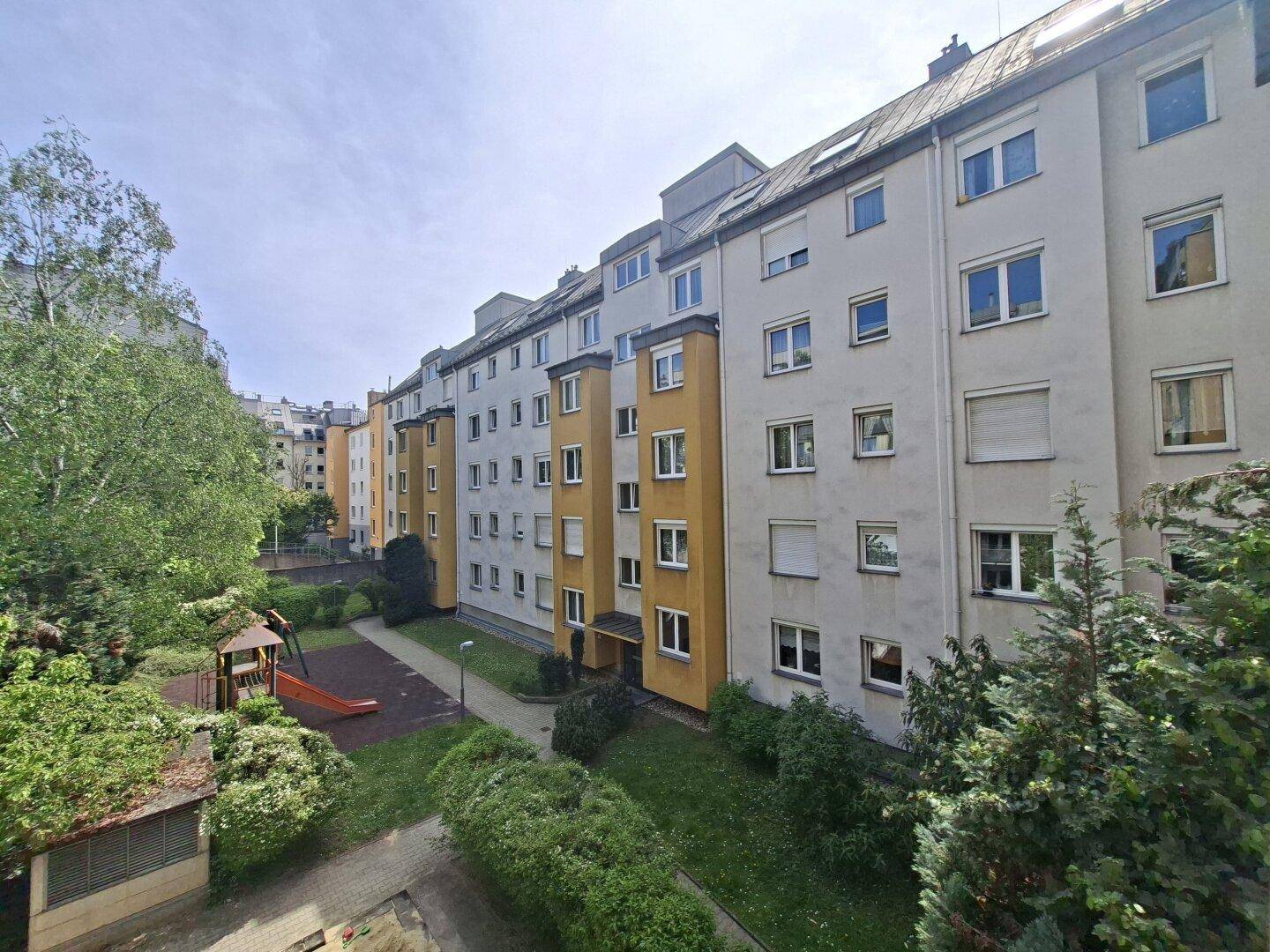 Fassade eines Mehrfamilienhauses mit gelben und hellen Abschnitten und Innenhofblick.