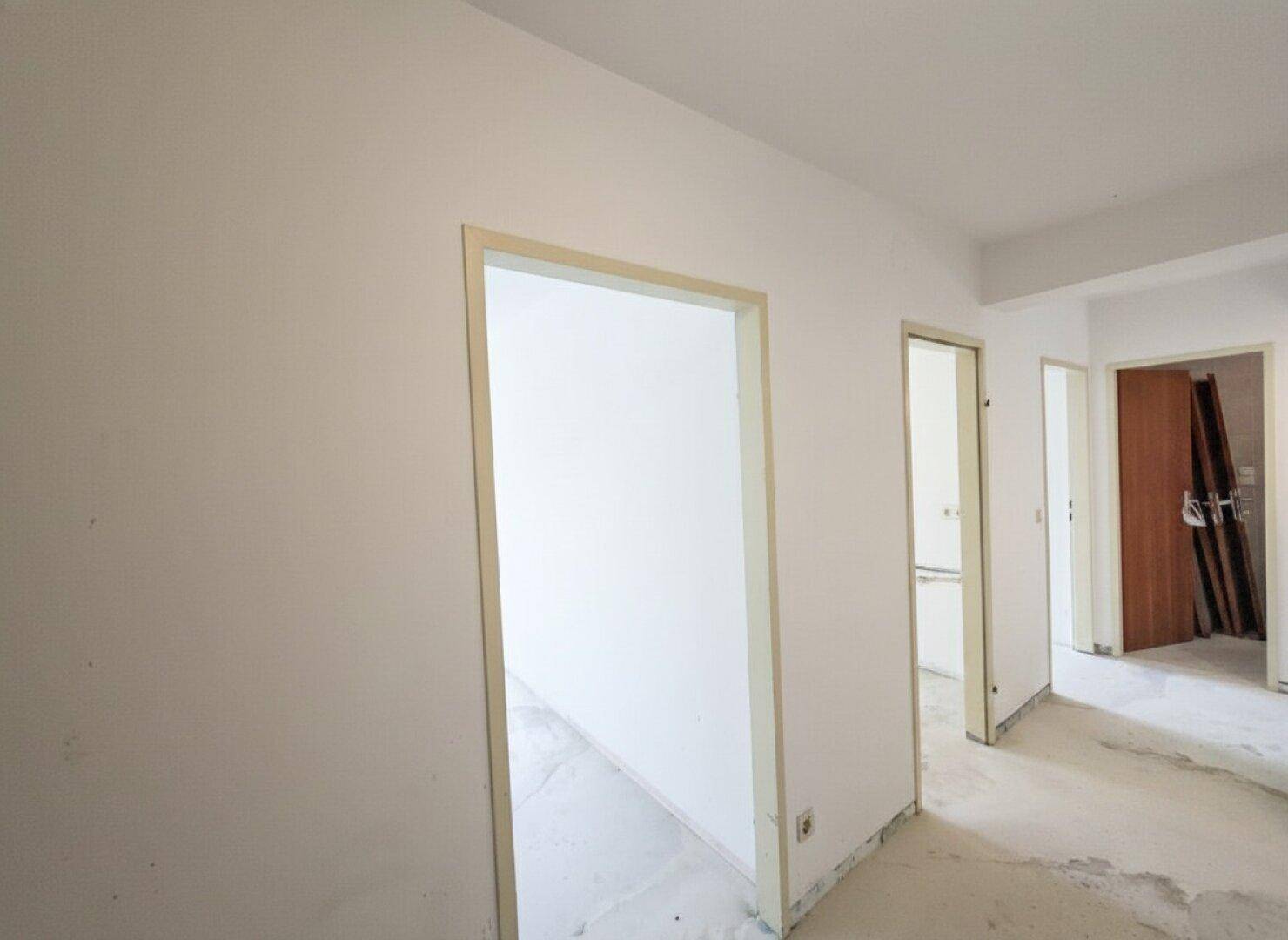 Flur mit mehreren Türöffnungen zu den unmöblierten Räumen der Wohnung.