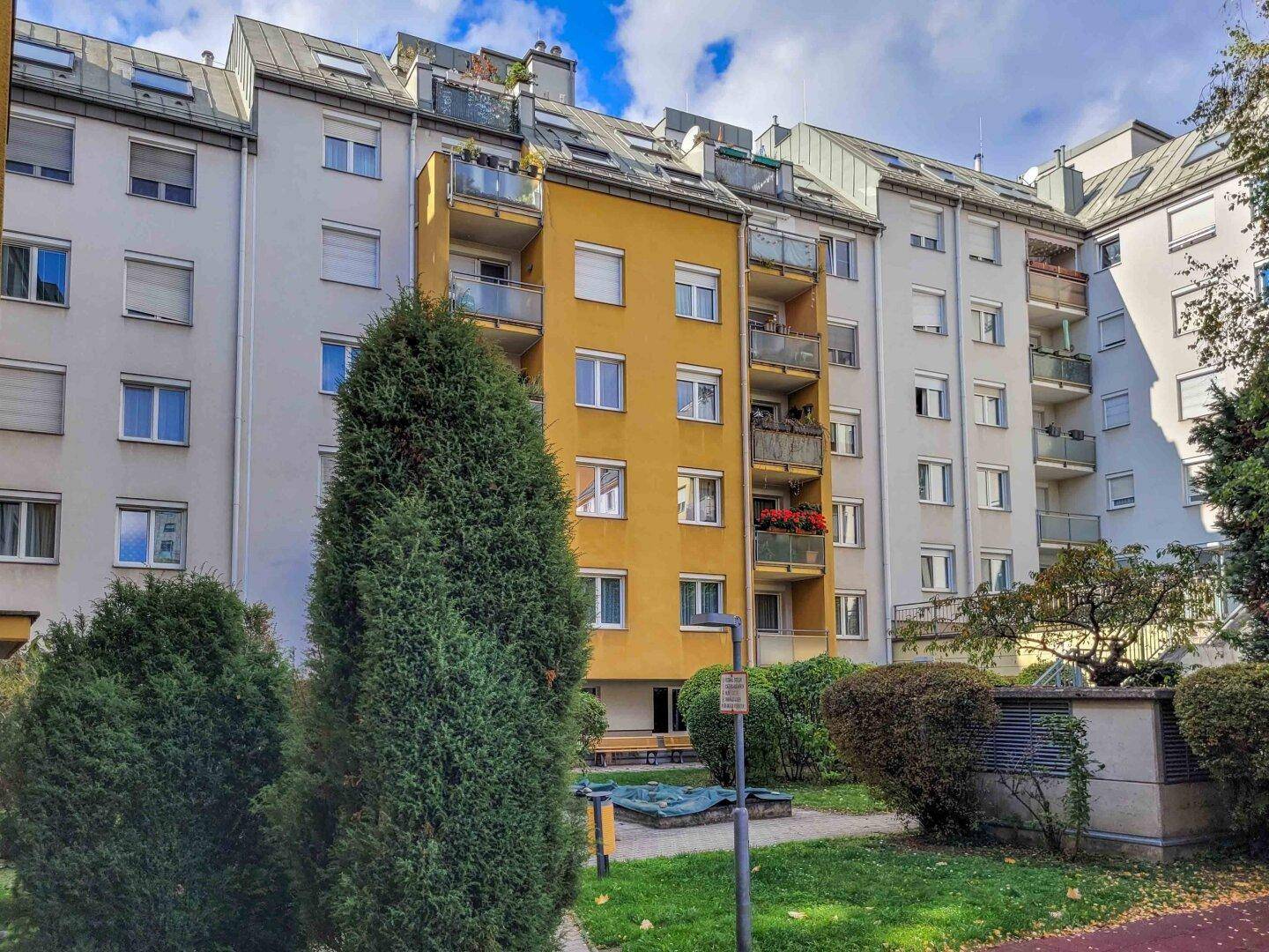 Mehrere Wohngebäude um einen begrünten Innenhof mit Spielplatz und Bäumen im Herbst.