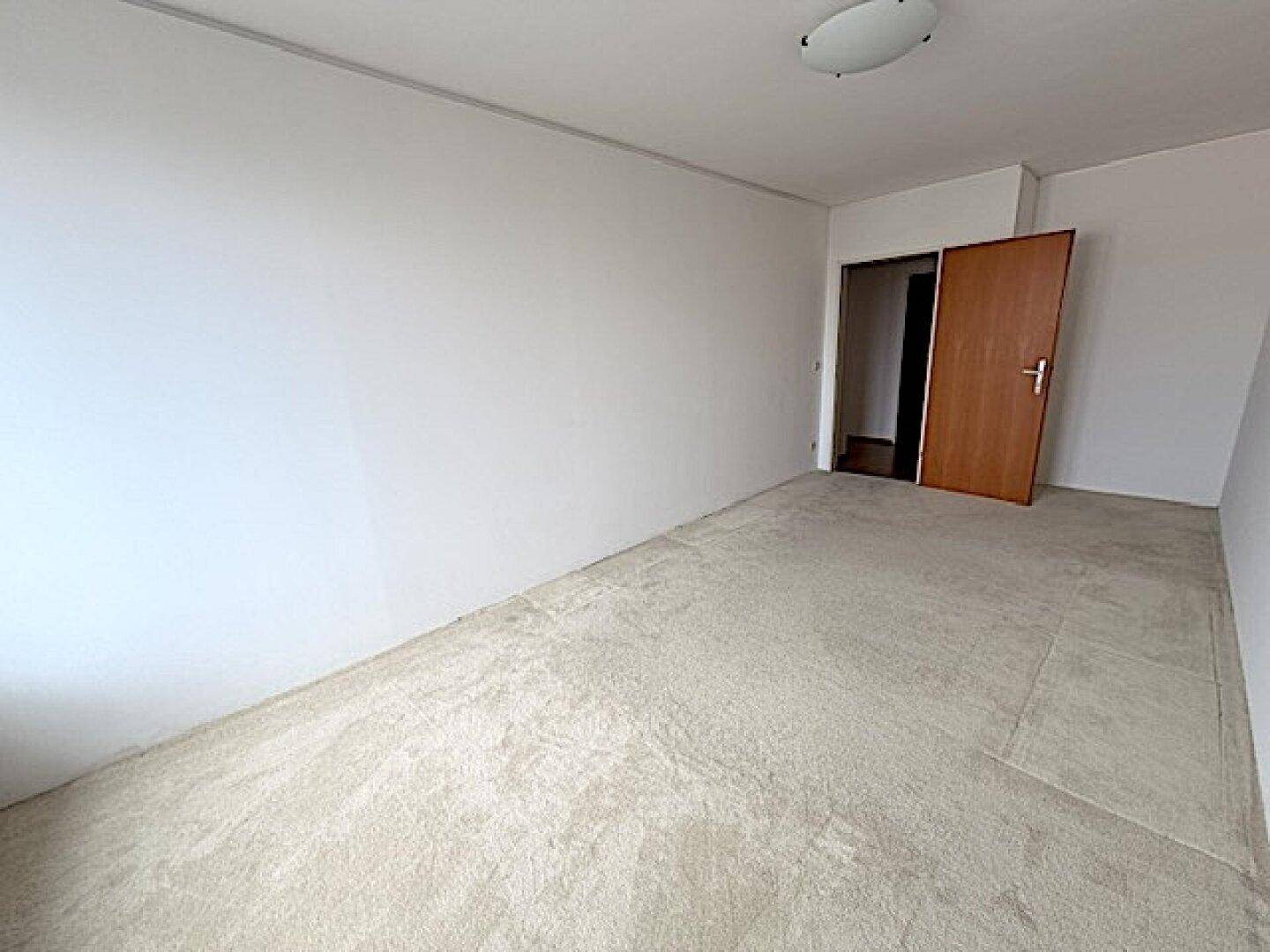 Ruhiges Schlafzimmer mit Teppichboden und weiß gestrichenen Wänden, ideal zum Entspannen.