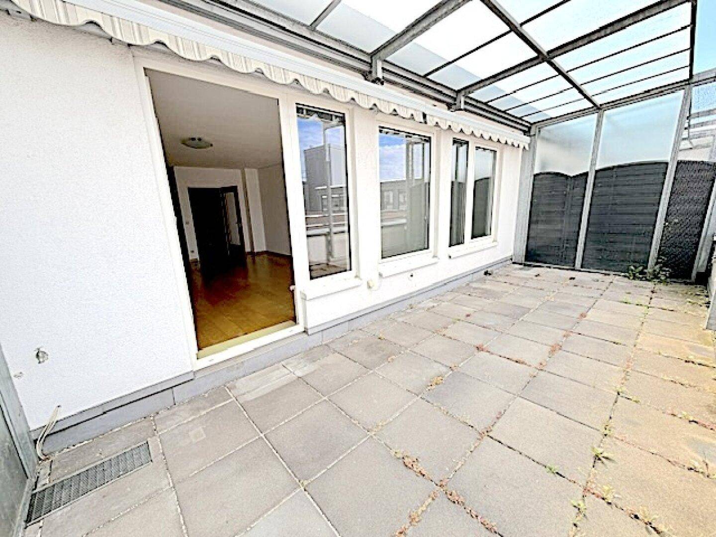 Geräumige Terrasse mit Fliesenboden und direktem Zugang zum Innenbereich durch eine große Tür.