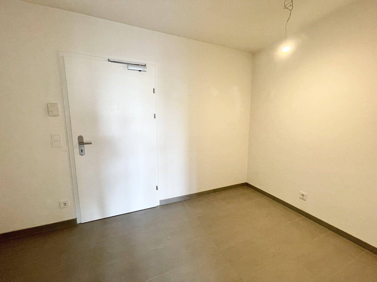 Kleiner, heller Raum mit Fliesenboden und einer weißen Tür.