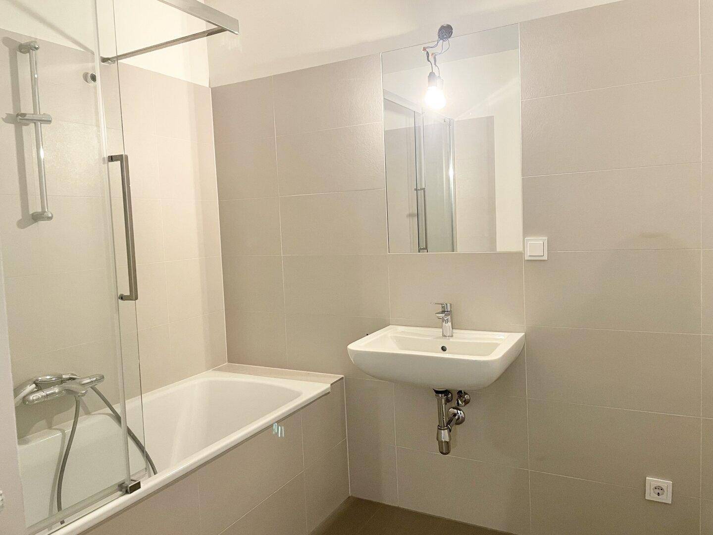 Modernes Badezimmer mit Badewanne, Dusche und hellem Fliesenboden.
