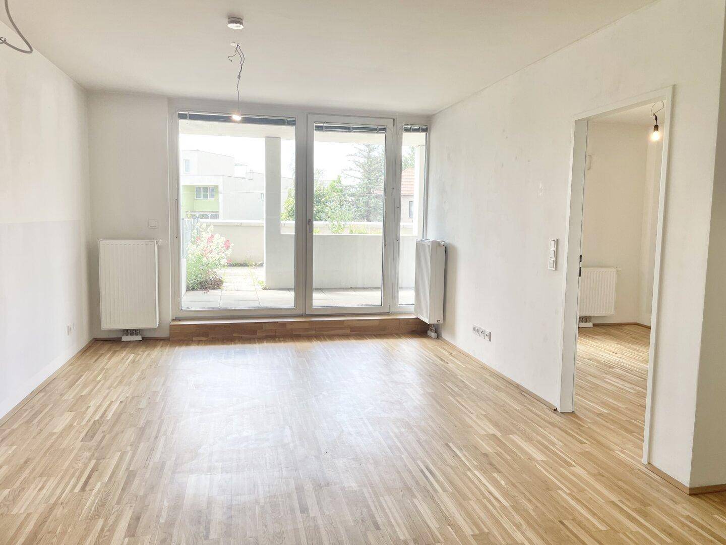Helles Wohnzimmer mit Parkettboden und Zugang zu einer großen Terrasse.