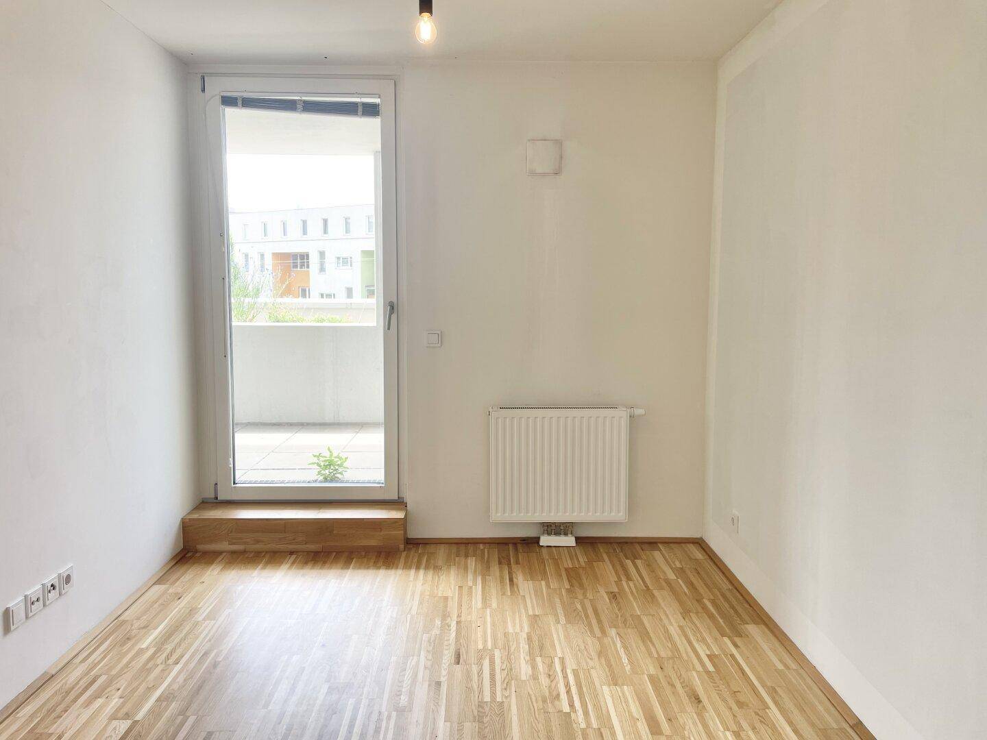 Helles Schlafzimmer mit Parkettboden und direktem Zugang zu einem Balkon.