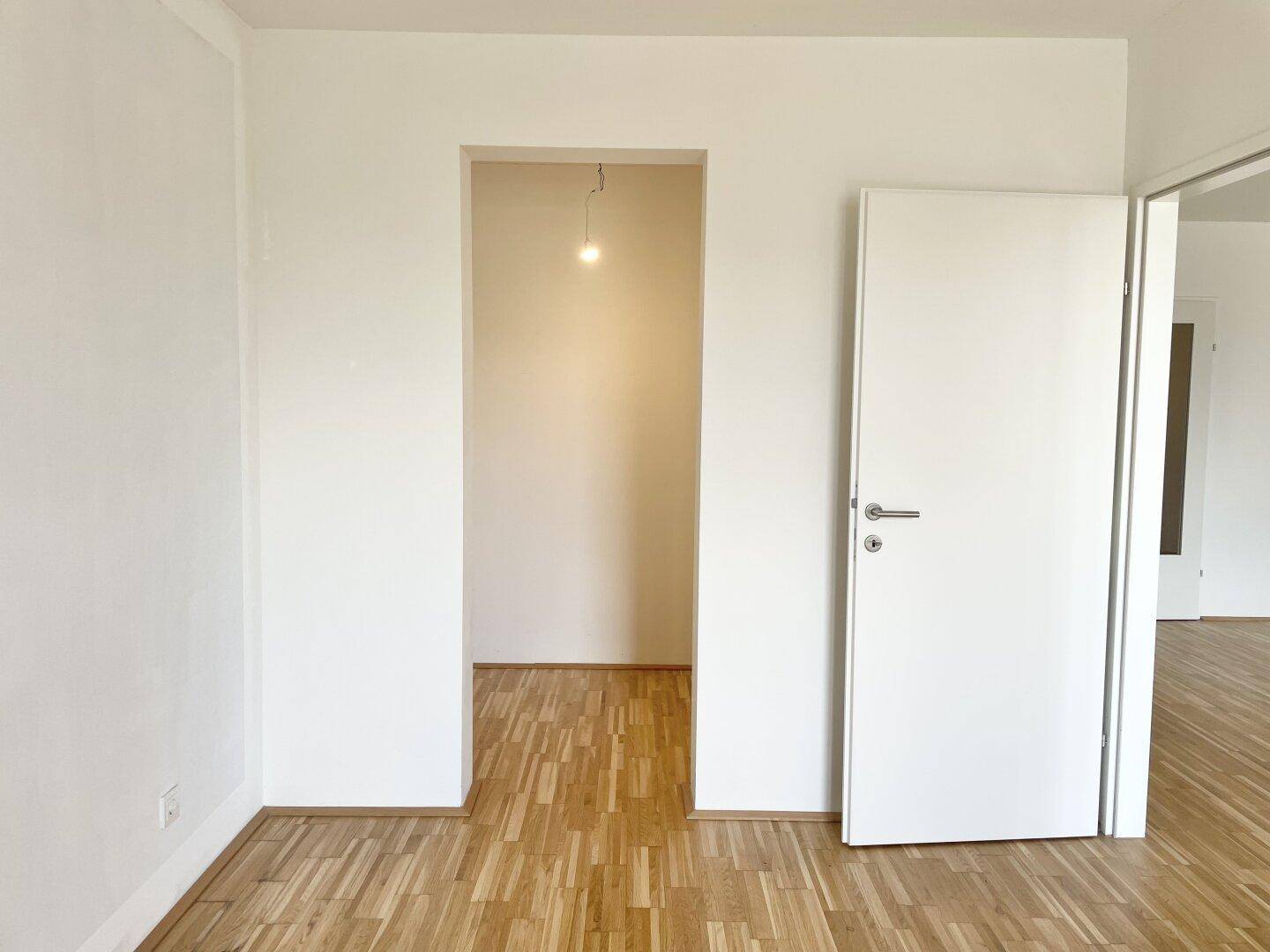 Heller Flur mit Parkettboden und weißen Türen, der zu weiteren Räumen führt.