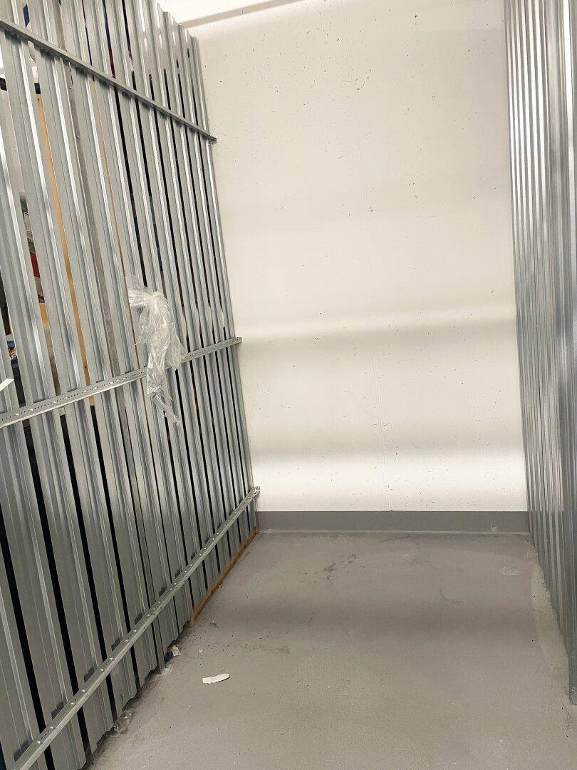 Lagerraum mit Metallabtrennungen und Betonboden für zusätzlichen Stauraum.